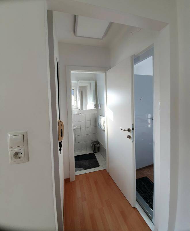 Heller Flur mit Holzboden, der zum Badezimmer und weiteren Räumen führt.