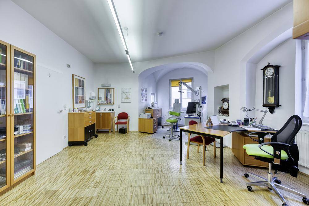 Helles und geräumiges Büro mit Holzboden, Bücherregalen und Arbeitsplätzen.