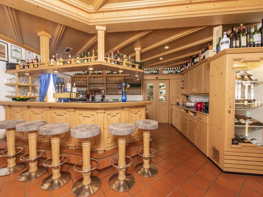 Gemütliche Bar im alpinen Stil mit Holzeinrichtung, Barhockern und einer großen Auswahl an Getränken.