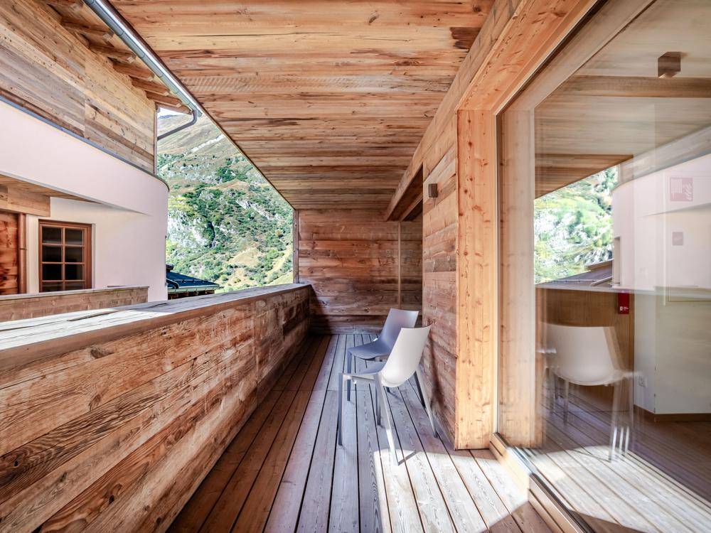 Holzbalkon mit Sitzgelegenheiten und weitem Blick auf die umliegende Berglandschaft.