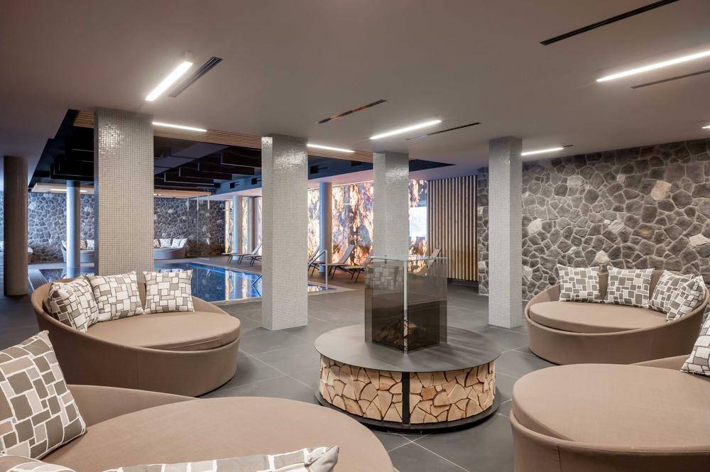 Exklusiver Wellnessbereich mit Pool, gemütlichen Liegeflächen und einem modernen Kamin.