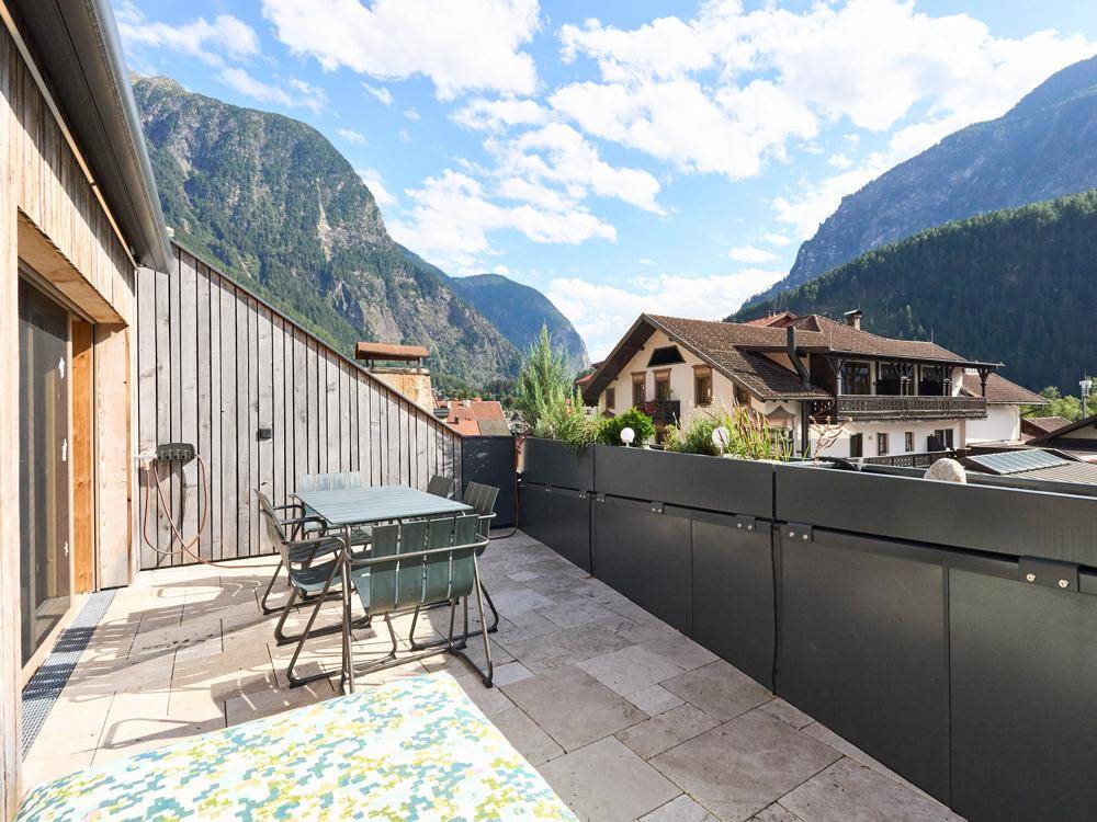 Geräumige Terrasse mit Sitzgelegenheiten und atemberaubendem Blick auf die umliegenden Berge.
