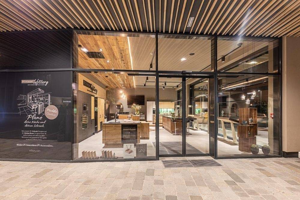 Eingangsbereich einer modernen Küchenausstellung mit großen Glasfenstern und Holzelementen.