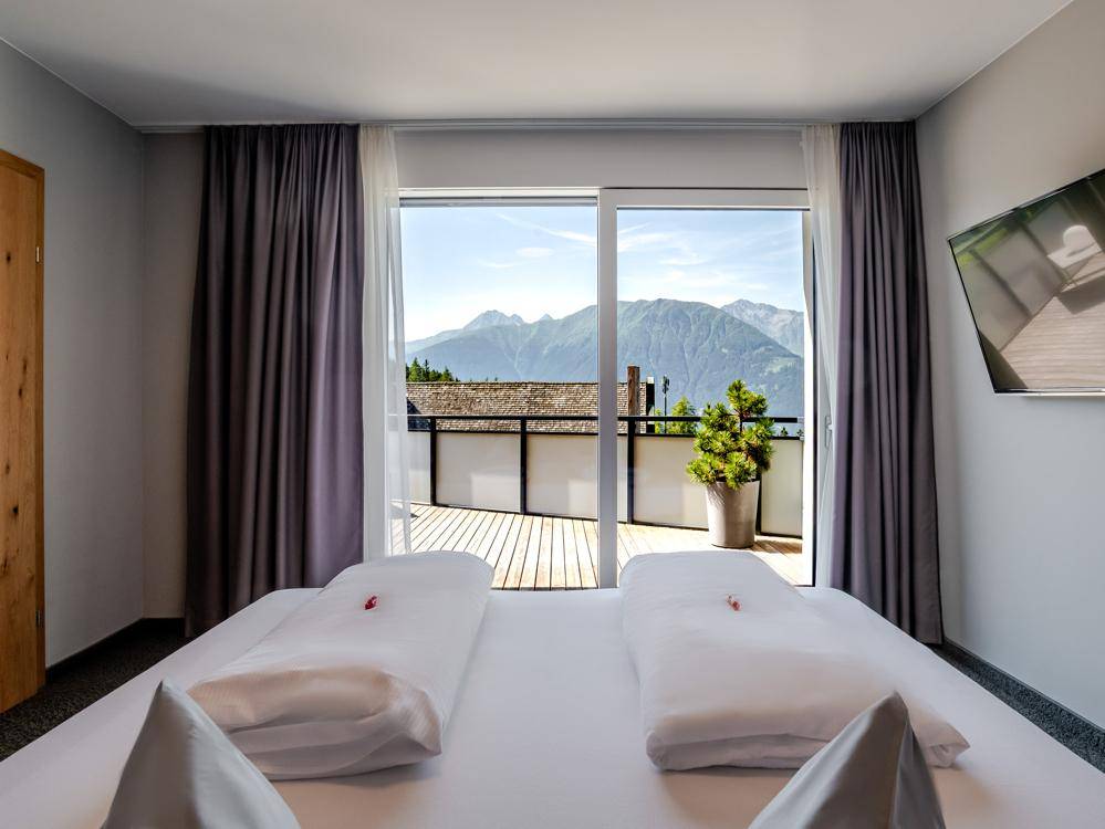 Helles Schlafzimmer mit Zugang zu einer Terrasse und einem atemberaubenden Blick auf die umliegende Bergwelt.