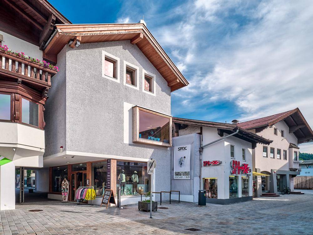 Außenansicht eines Gebäudes mit moderner Architektur, großen Fenstern und traditionellen Holzelementen.