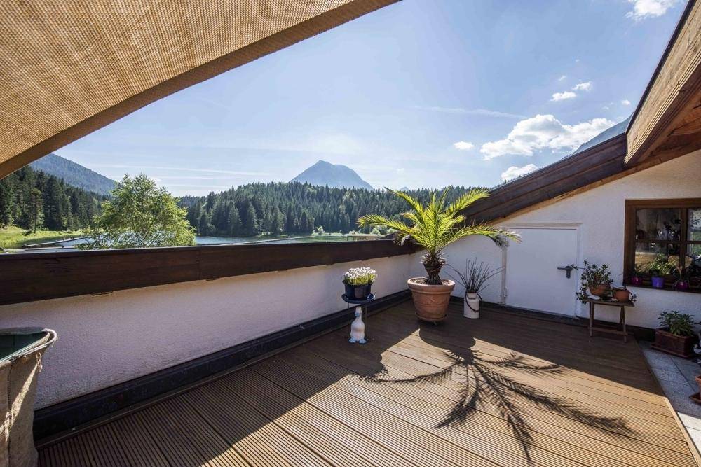 Geräumige Dachterrasse mit Holzboden, Sonnenschutz und weitem Blick auf die umliegende Berglandschaft.
