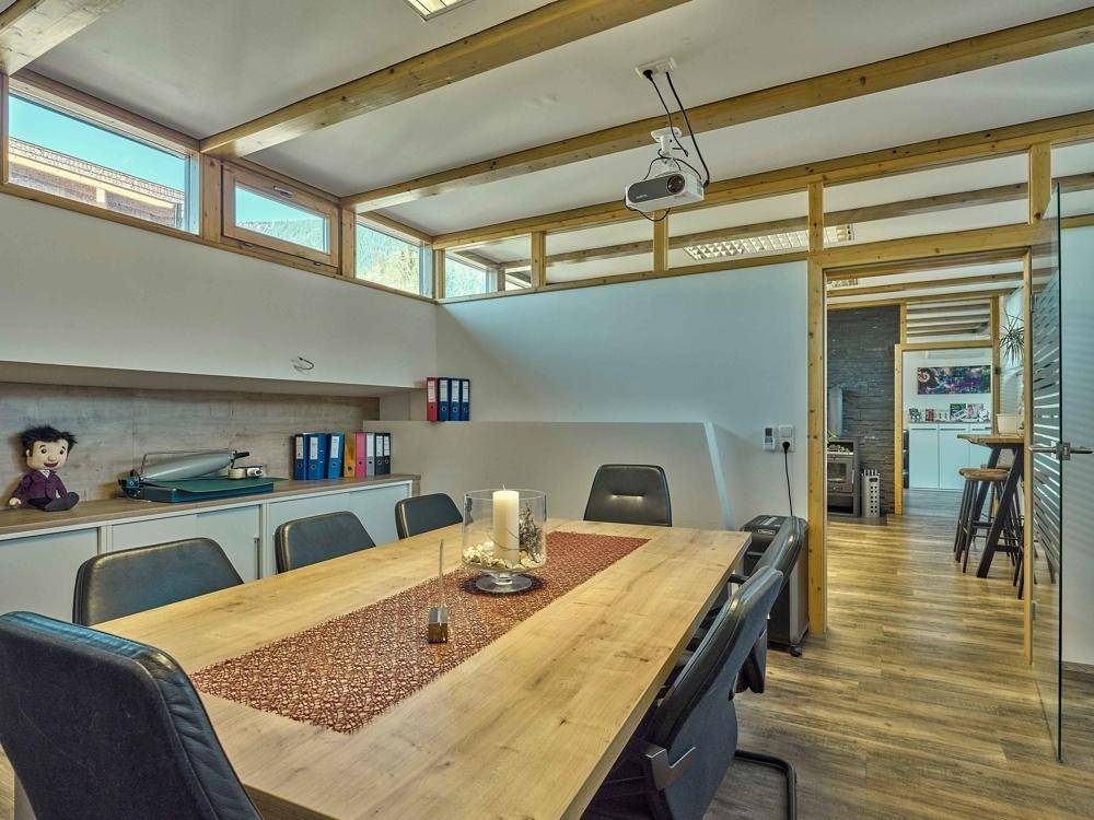 Konferenzraum mit großem Holztisch, Projektor und Holzbalken, ideal für produktive Besprechungen und Präsentationen.