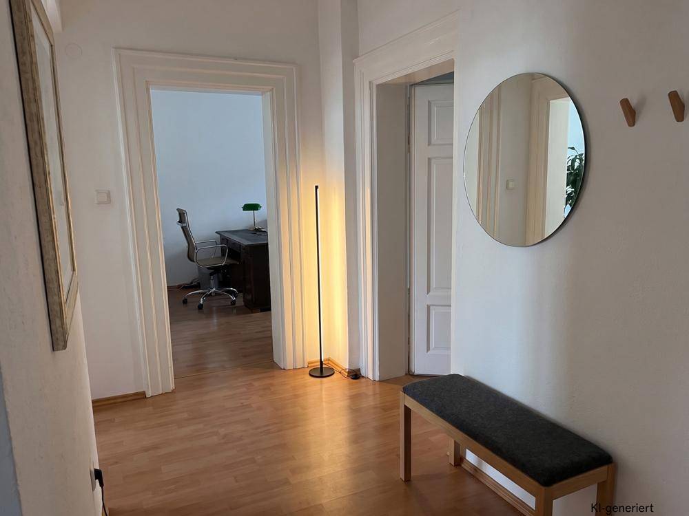 Ein heller Flur mit Holzboden, einem runden Spiegel und einem Blick in ein angrenzendes Arbeitszimmer.