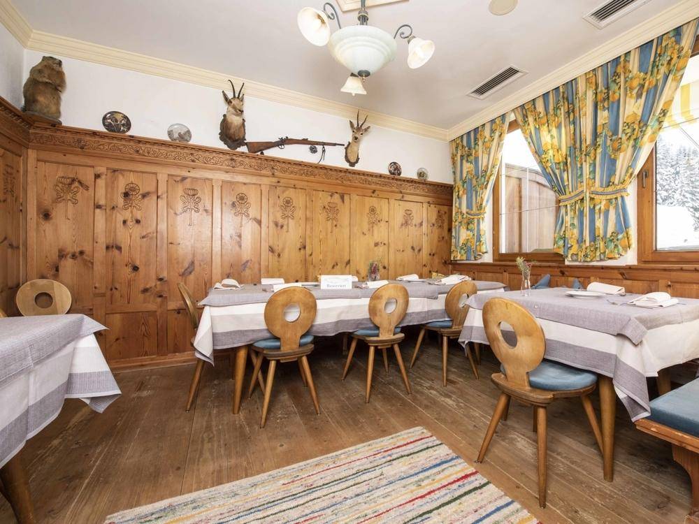 Rustikaler Speisesaal mit Holzböden und -wänden, dekoriert mit Jagdtrophäen und traditionellen Möbeln.