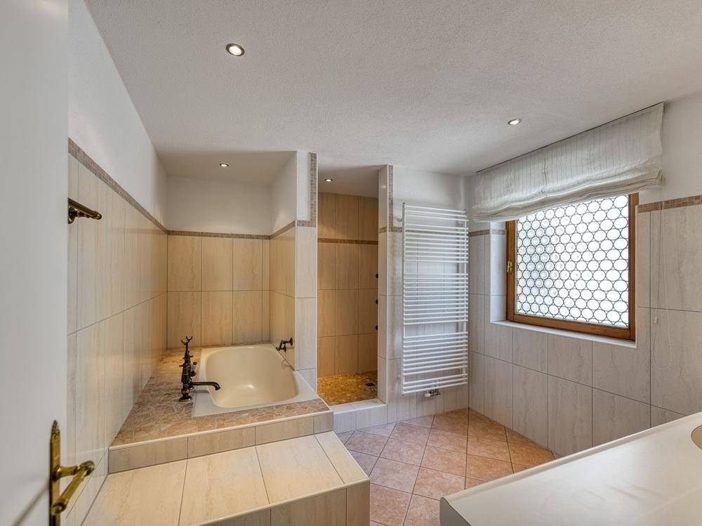 Geräumiges Badezimmer mit Badewanne, separater Dusche und Fenster für Tageslicht.