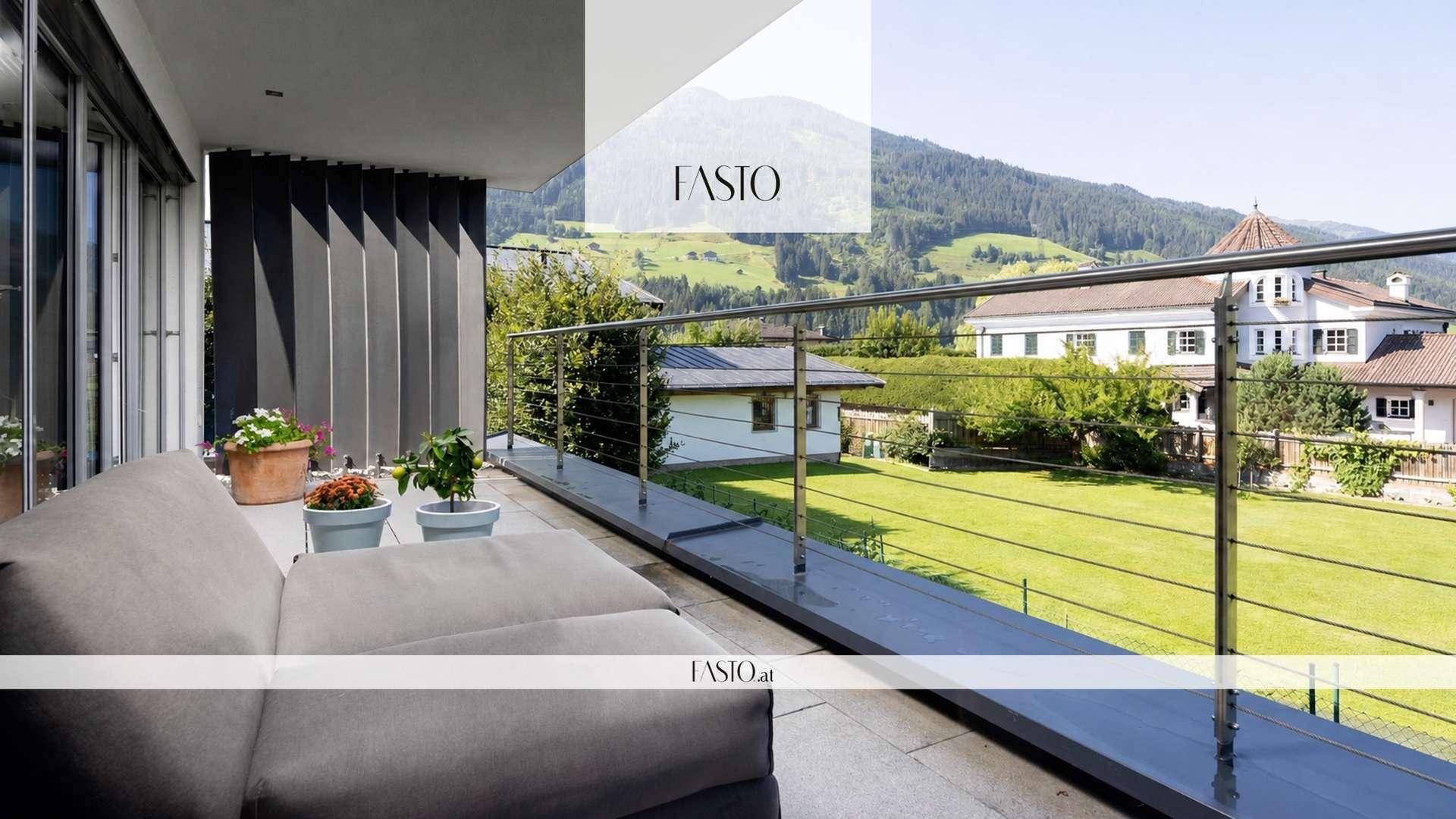 Geräumiger Balkon mit bequemen Loungemöbeln und weitem Blick auf die umliegenden Berge und grüne Wiesen.