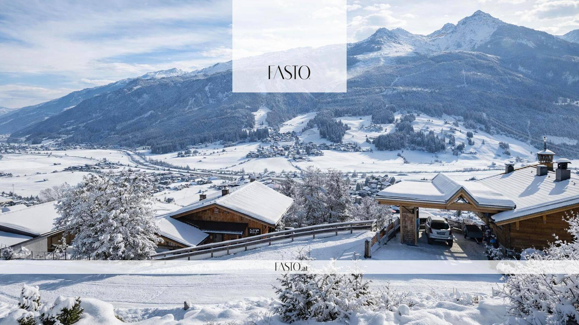 Winterliche Landschaft mit verschneiten Häusern und majestätischen Bergen unter blauem Himmel.