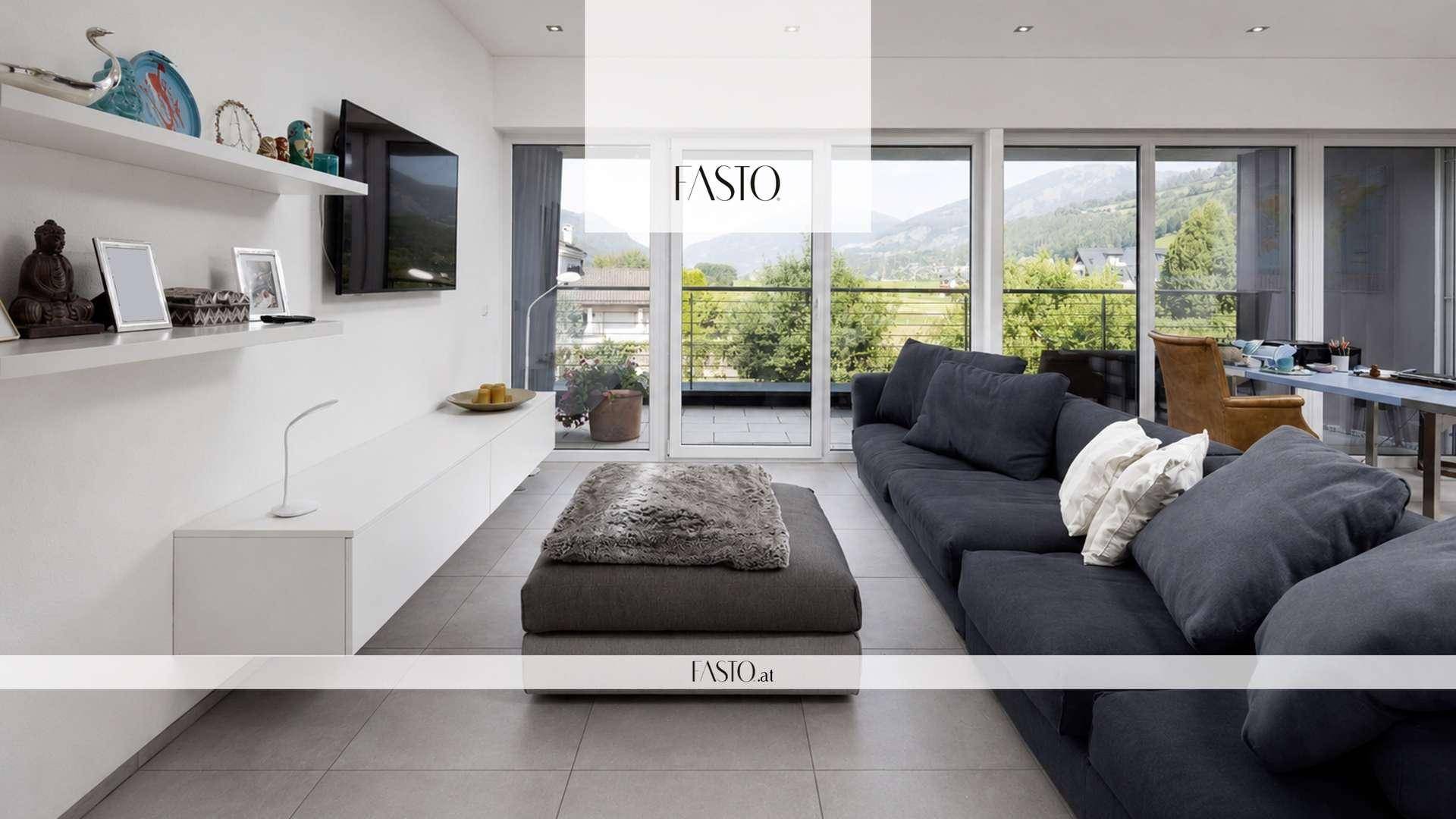 Helles Wohnzimmer mit modernen Möbeln, Fliesenboden und großen Fenstern mit Bergblick und Balkonzugang.