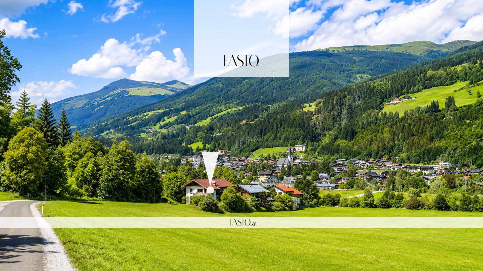 Panoramablick auf ein Haus in einer grünen Talandschaft mit Dorf und Bergen im Hintergrund.