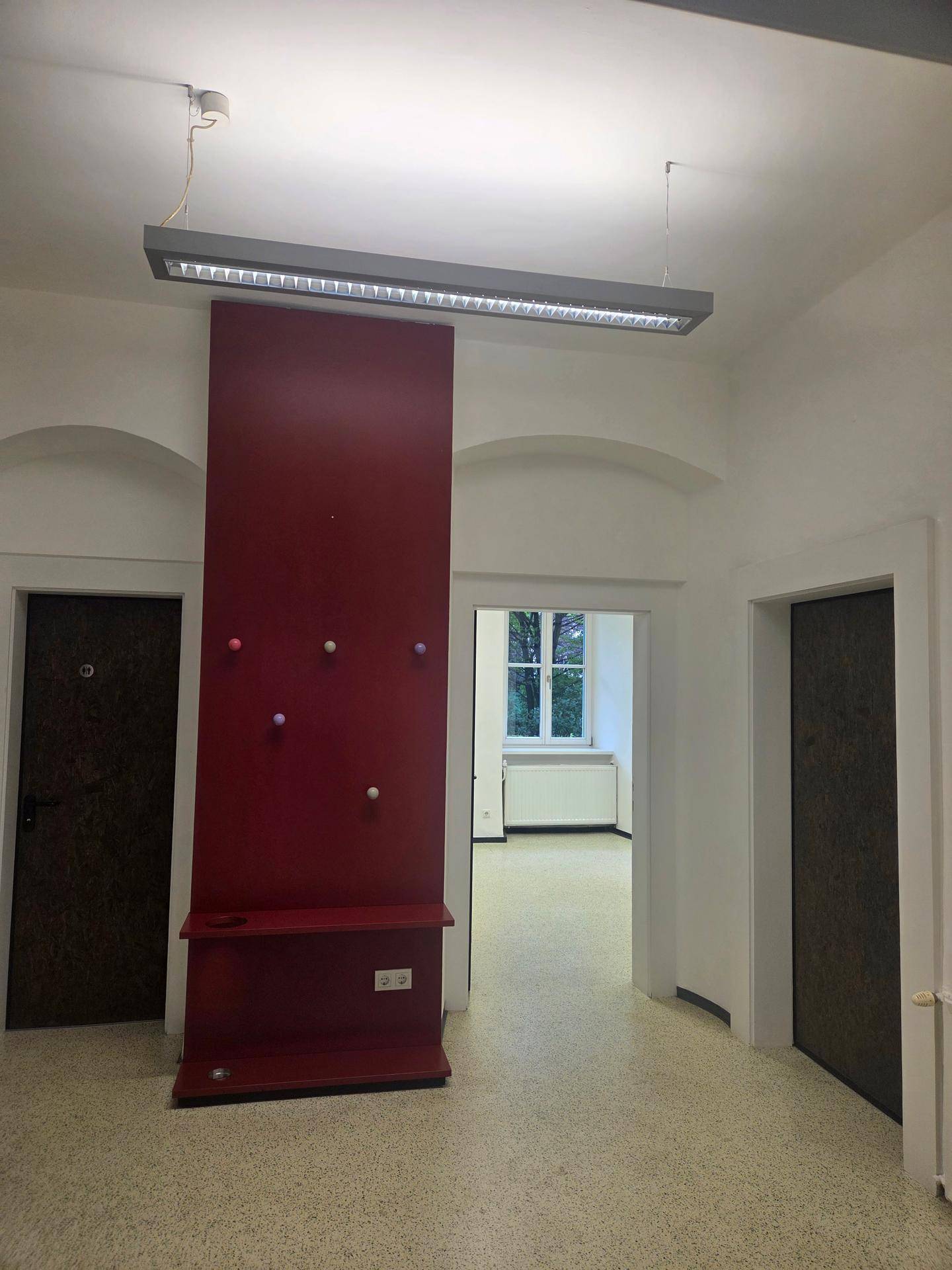 Flur mit roter Wandverkleidung und mehreren Türen, die zu verschiedenen Räumen führen.