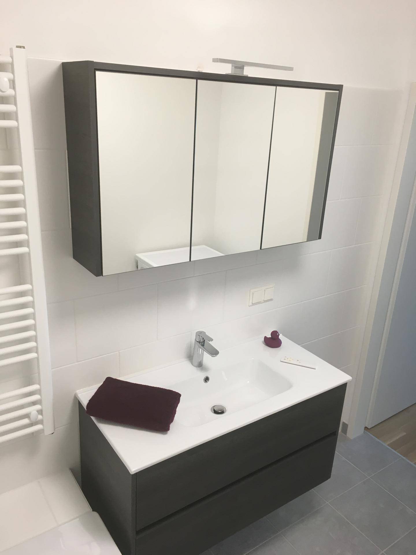 Modernes Badezimmer mit Waschtisch, großem Spiegelschrank und beheiztem Handtuchhalter.