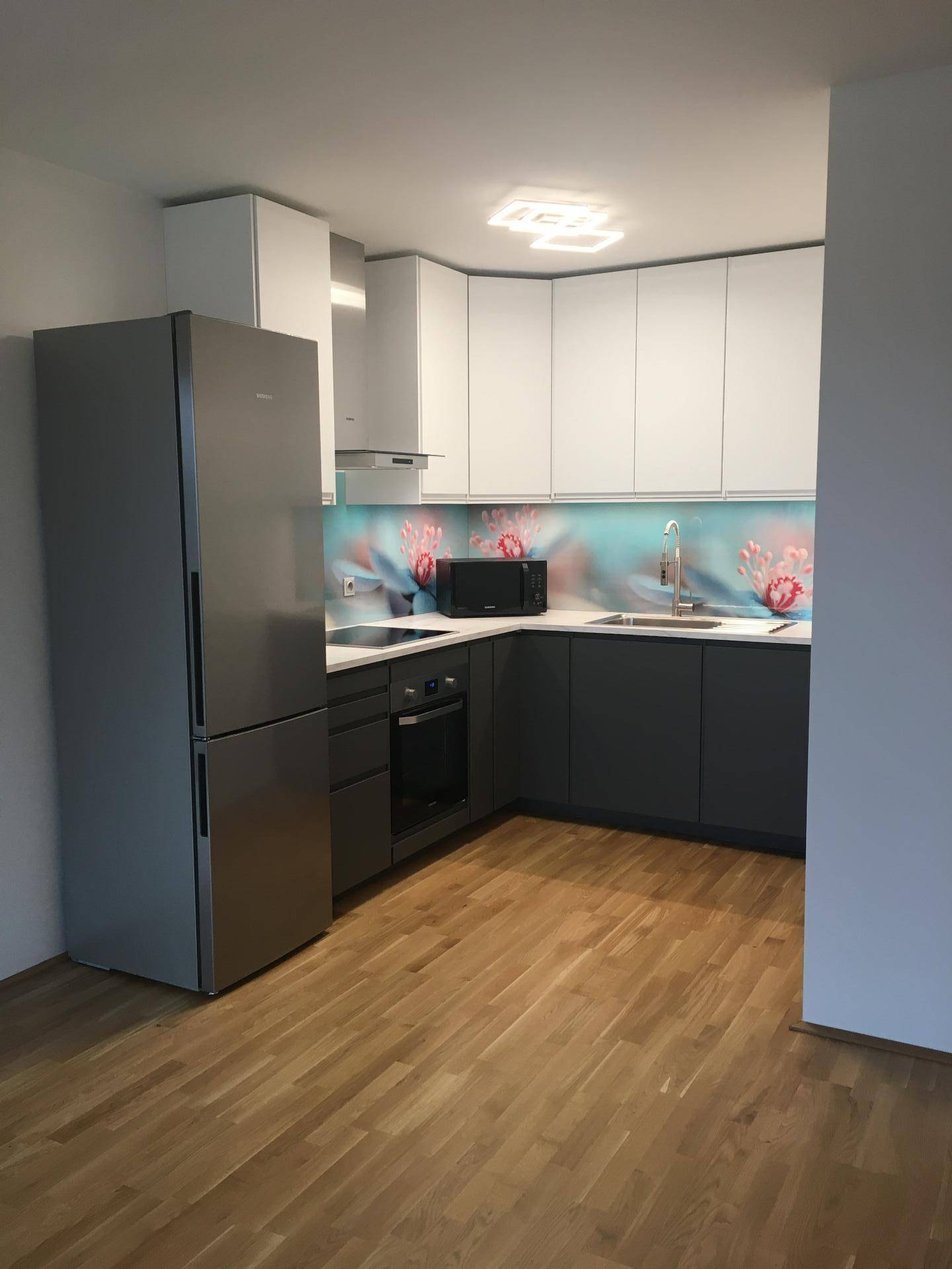 Geräumige Küche mit moderner Ausstattung, hellen und dunklen Schränken sowie Laminatboden.