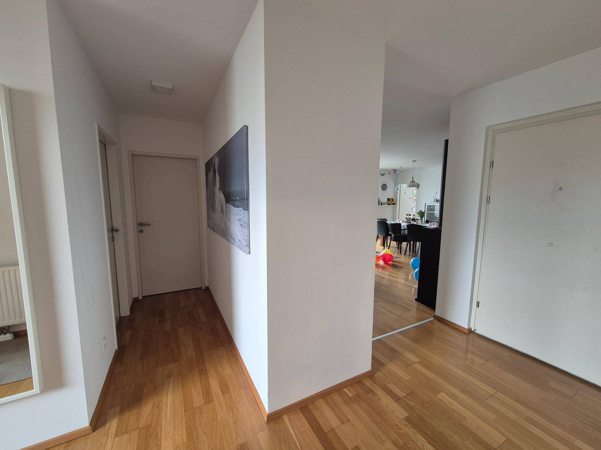 Heller Flur mit Holzfußboden, der in einen offenen Wohn- und Essbereich führt.