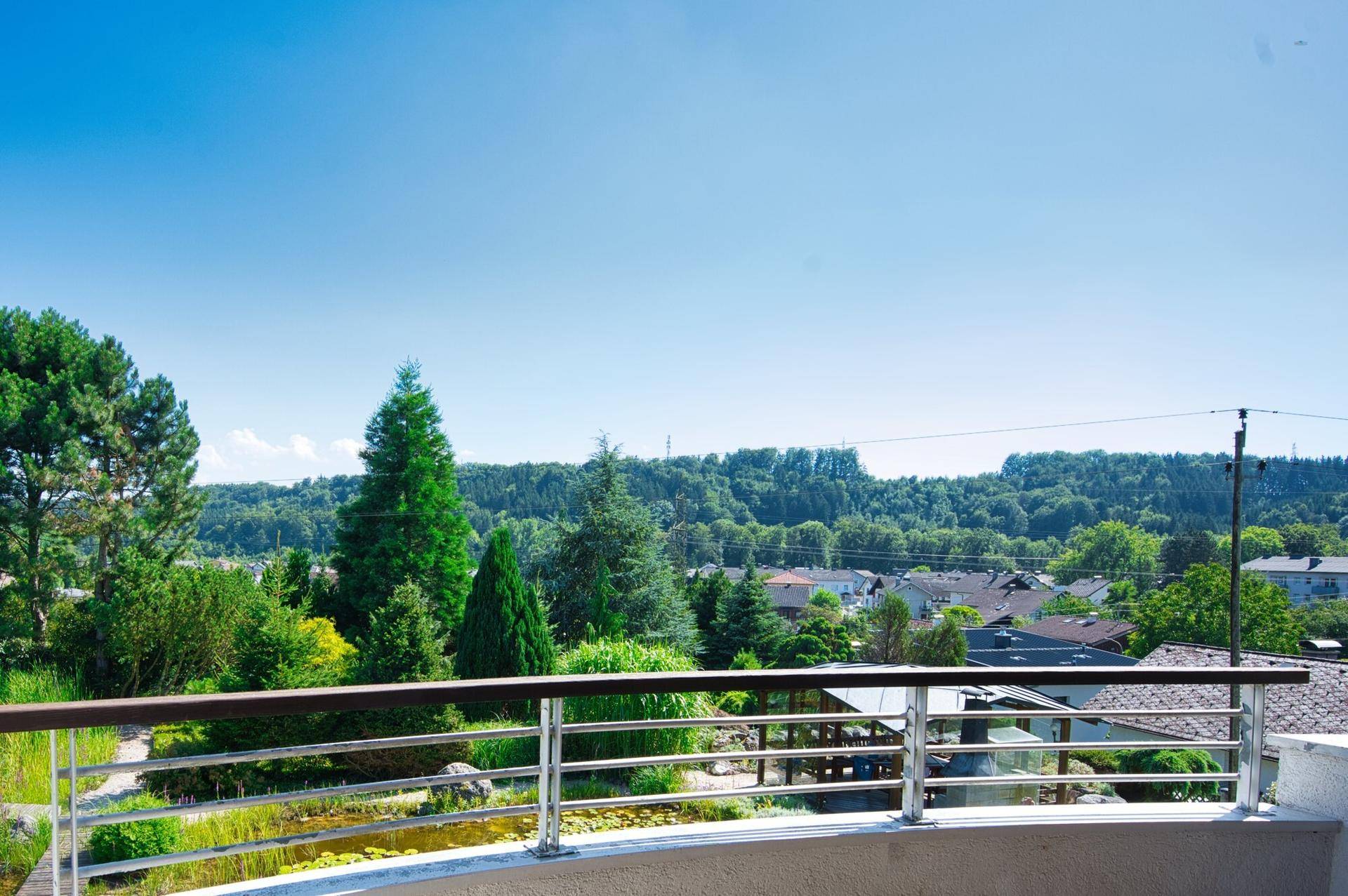 Weitläufiger Ausblick vom Balkon über grüne Hügel und die umliegende Wohnsiedlung.