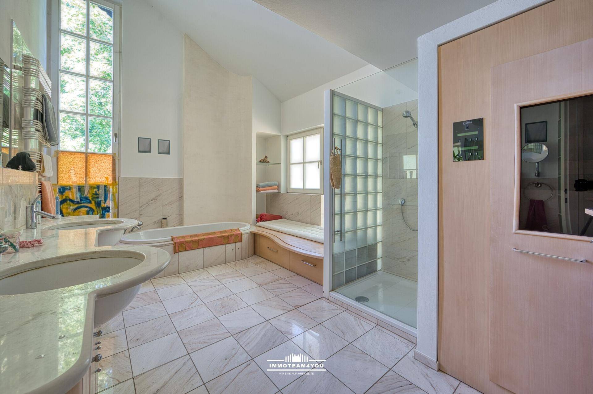 Großes Badezimmer mit Doppelwaschbecken, Badewanne und separater Dusche mit Glasbausteinen.