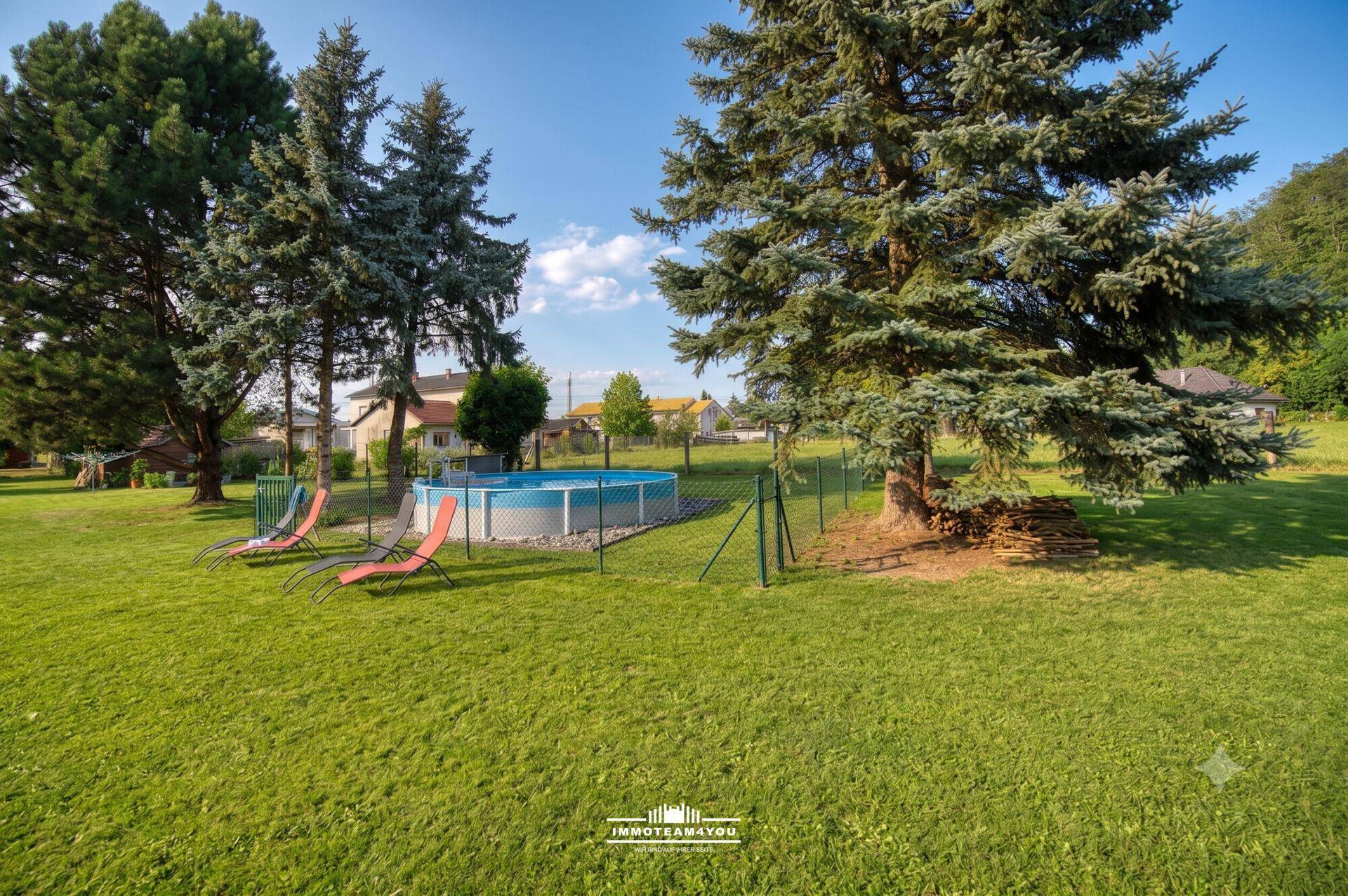 Weitläufiger Garten mit Aufstellpool, großen Bäumen und viel Grünfläche.