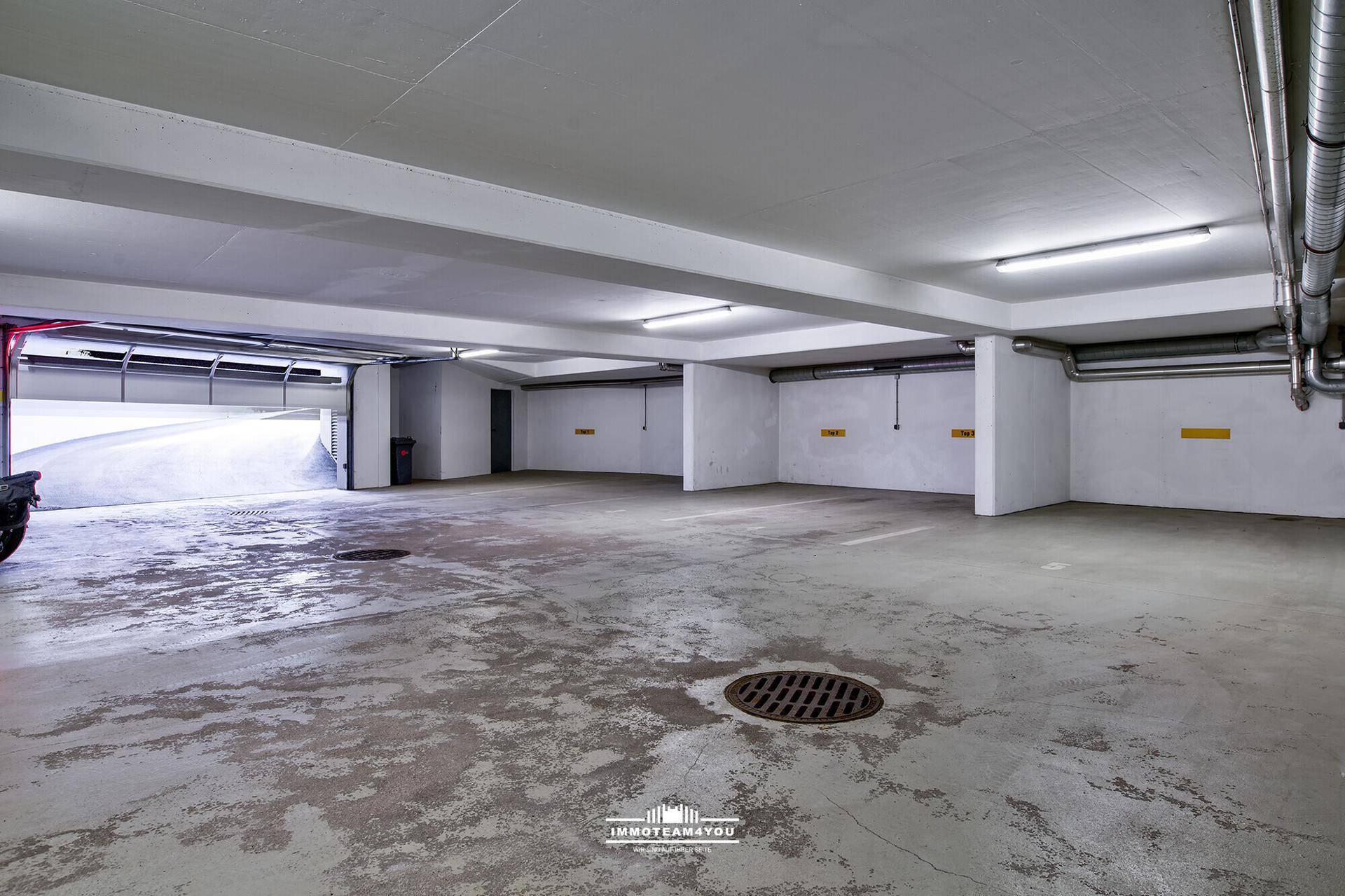 Geräumige Tiefgarage mit Betonboden und ausreichend Parkplätzen.