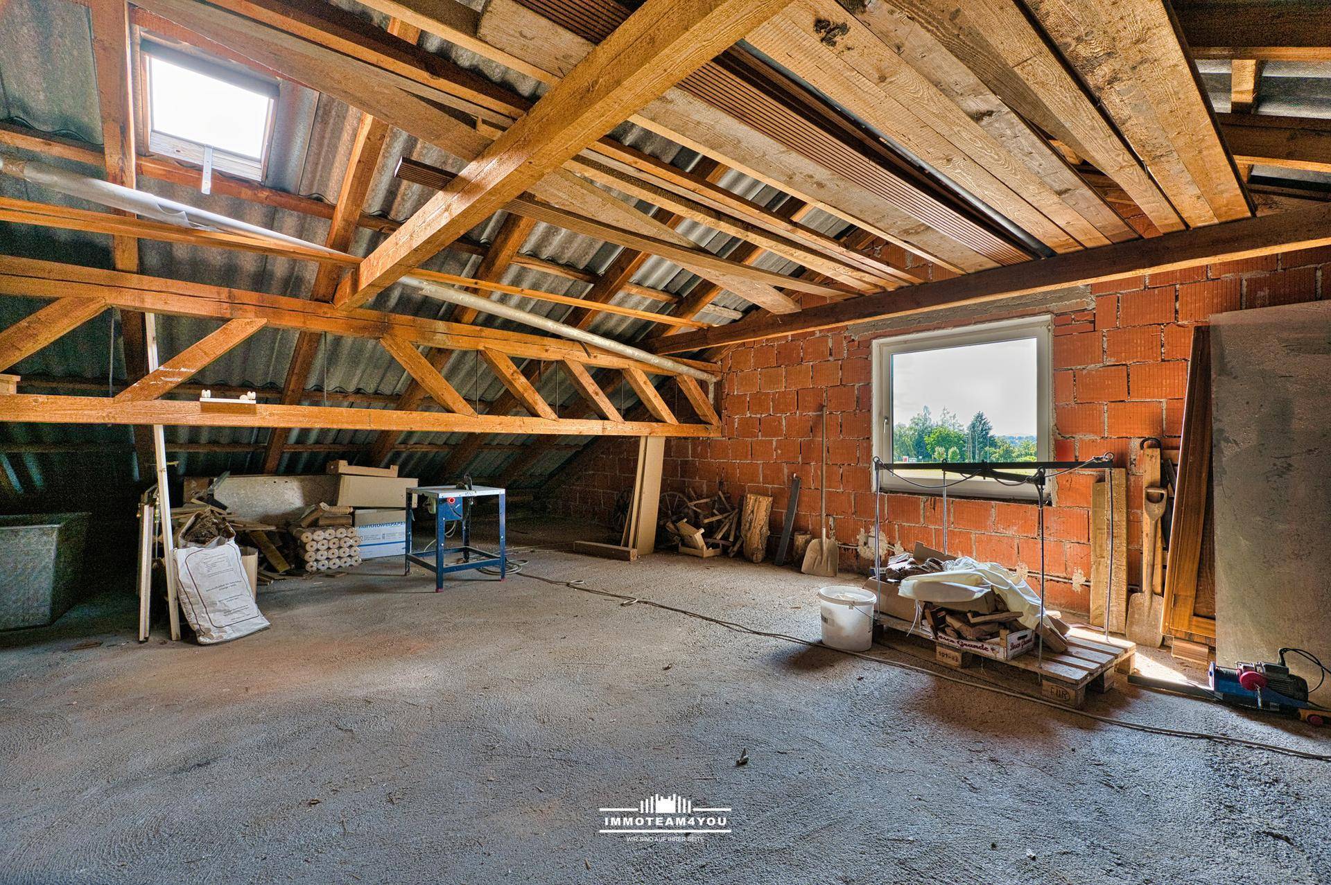 Unausgebauter Dachboden mit sichtbaren Holzbalken, Fenster und viel Stauraum.