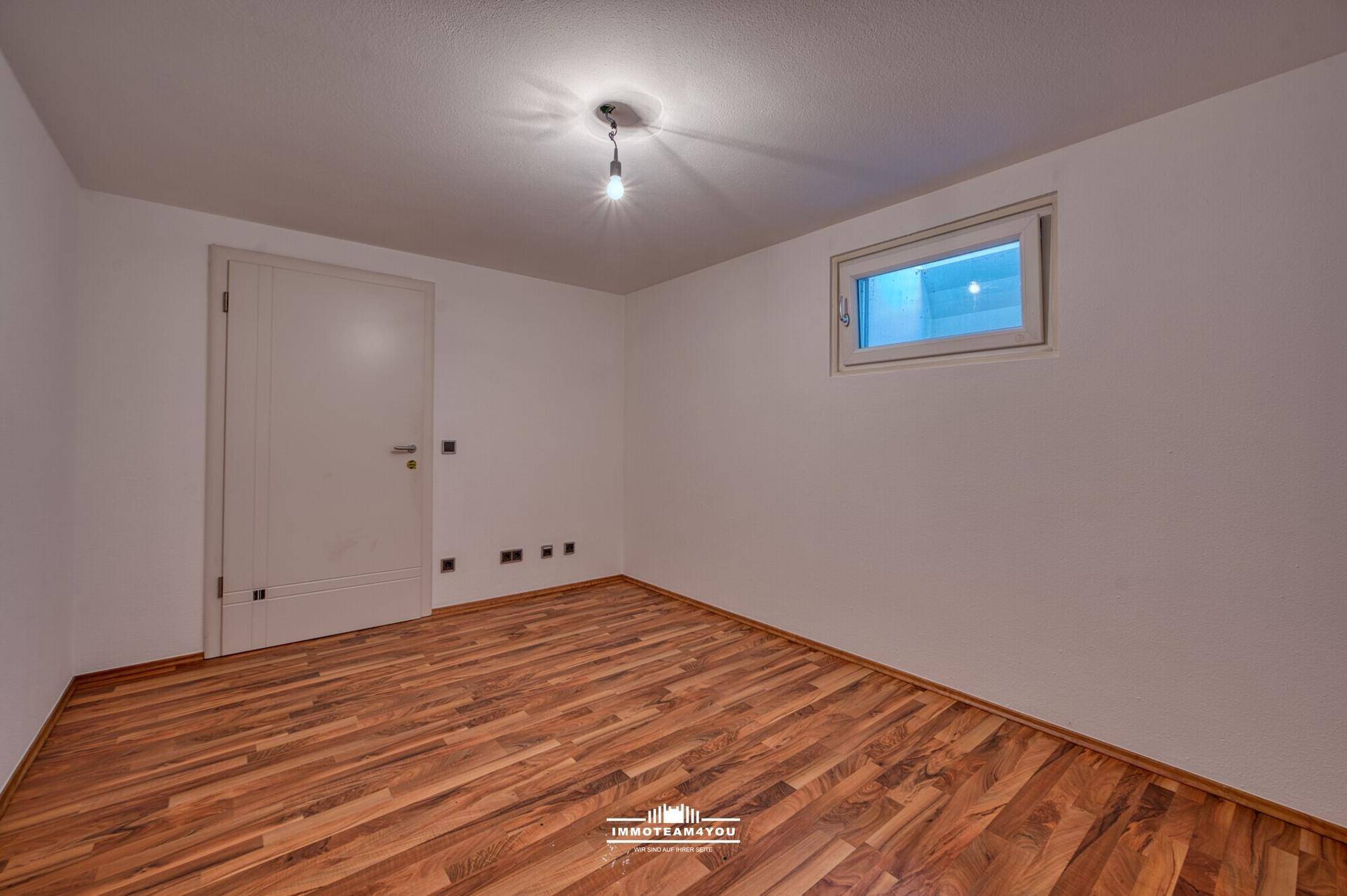 Helles Zimmer im Dachgeschoss mit Laminatboden und Tür.