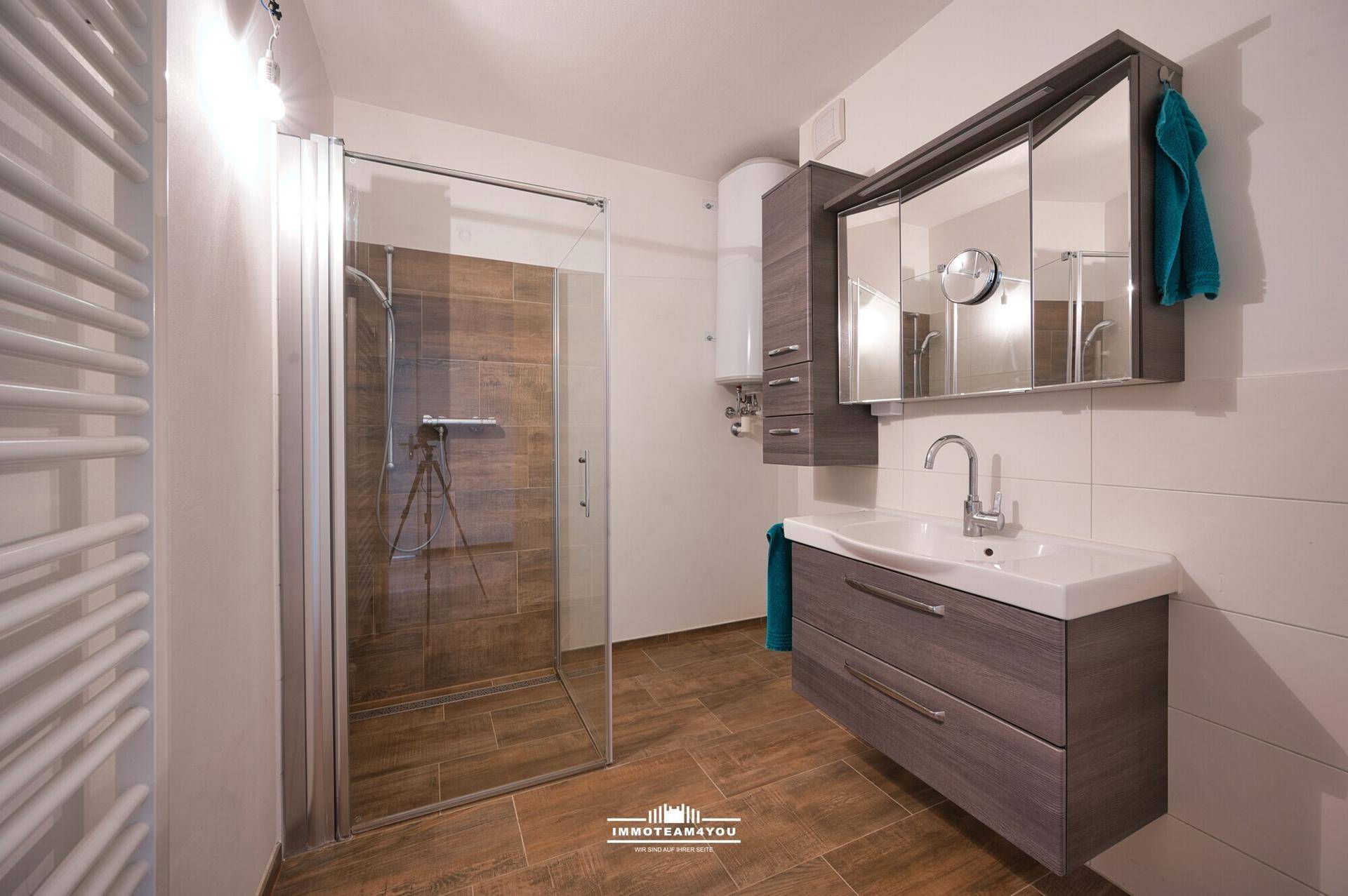 Modernes Badezimmer mit ebenerdiger Dusche, Waschtisch und beheiztem Handtuchhalter.