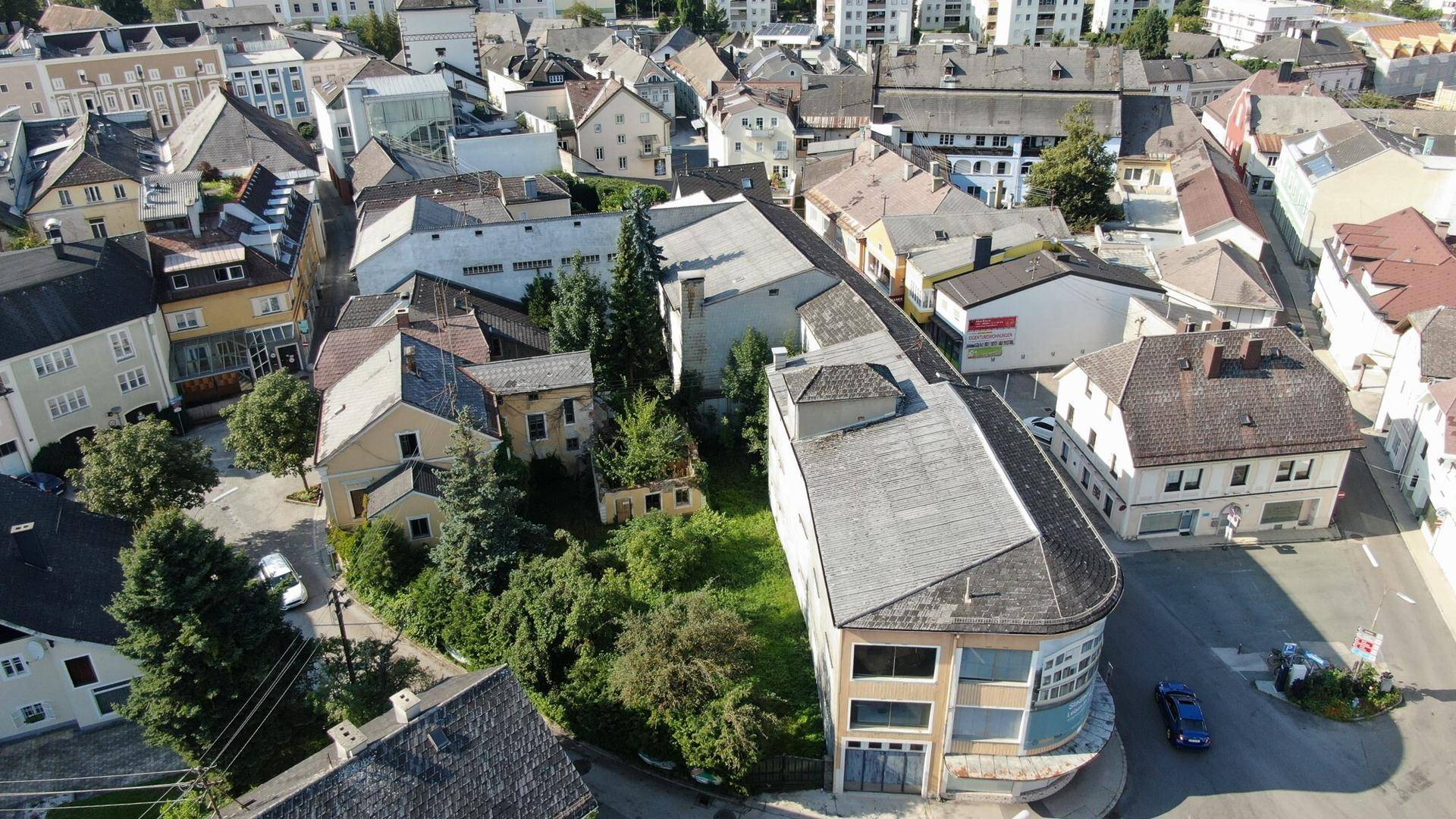 Luftaufnahme eines älteren Gebäudekomplexes mit Sanierungsbedarf und umliegenden Grünflächen in der Stadt.