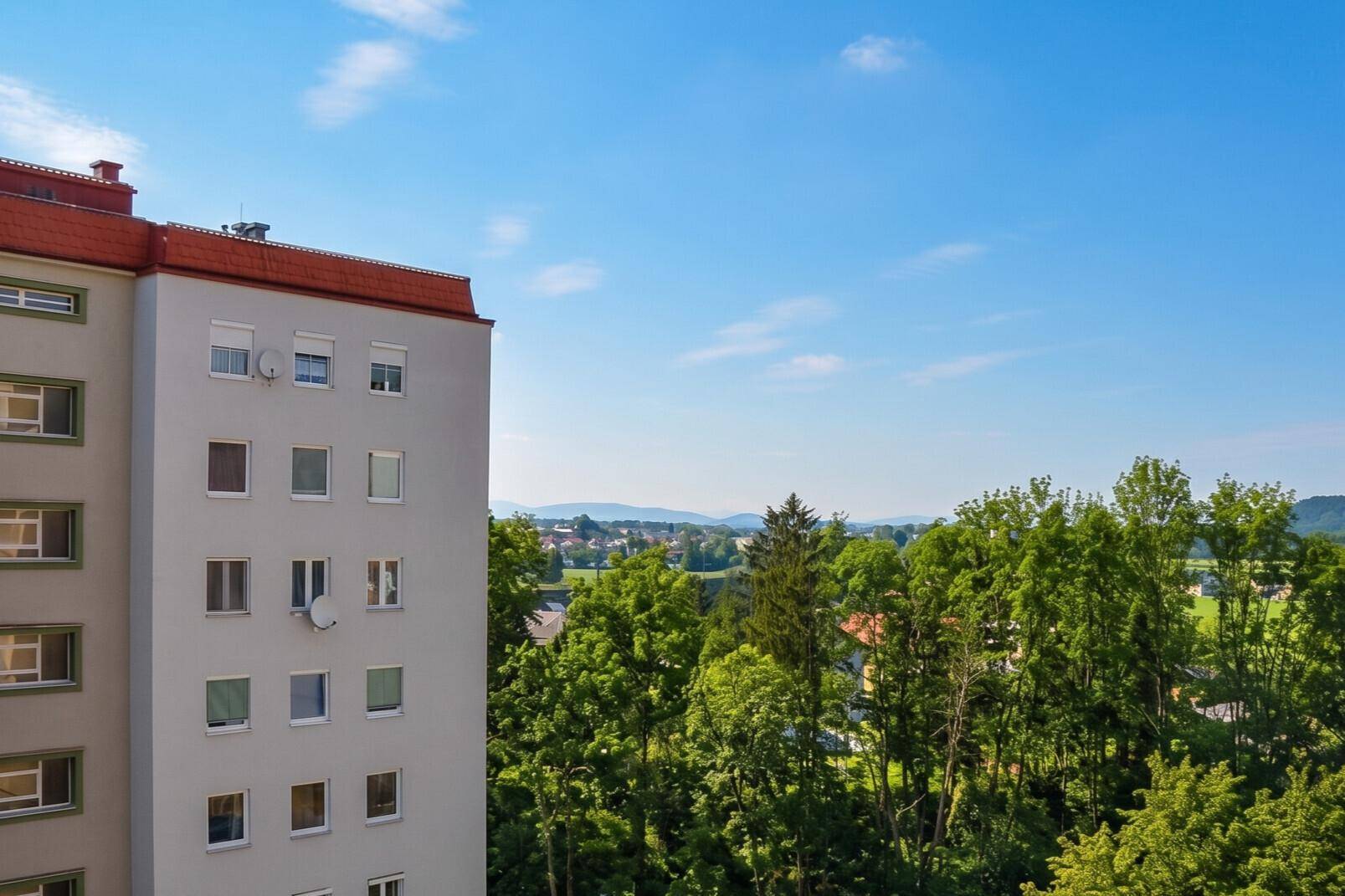 Wohngebäude umgeben von üppigem Grün mit weitem Blick über die Landschaft.