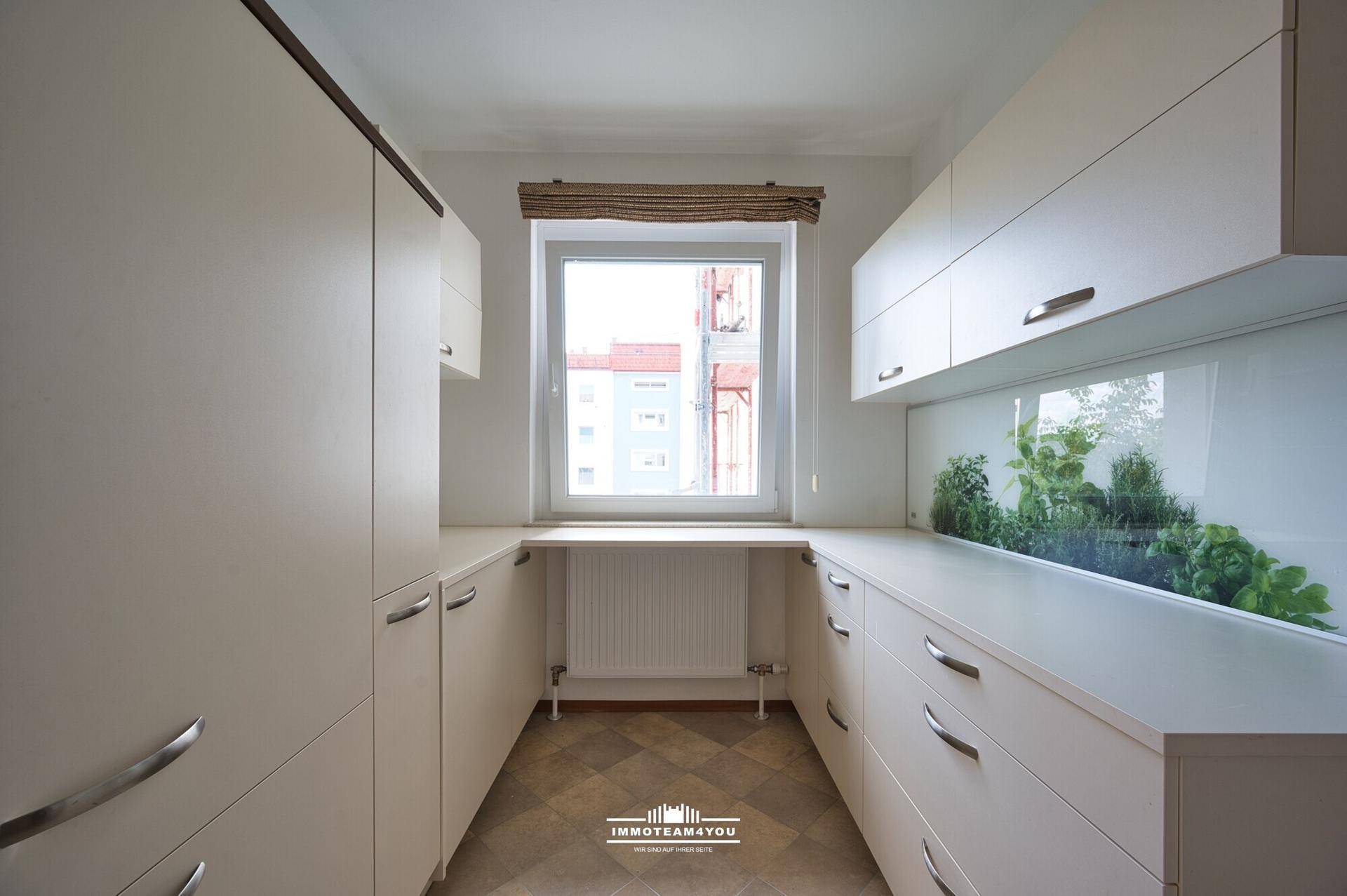 Helle Küche mit viel Stauraum, Fenster und Heizkörper, ideal für effizientes Kochen.