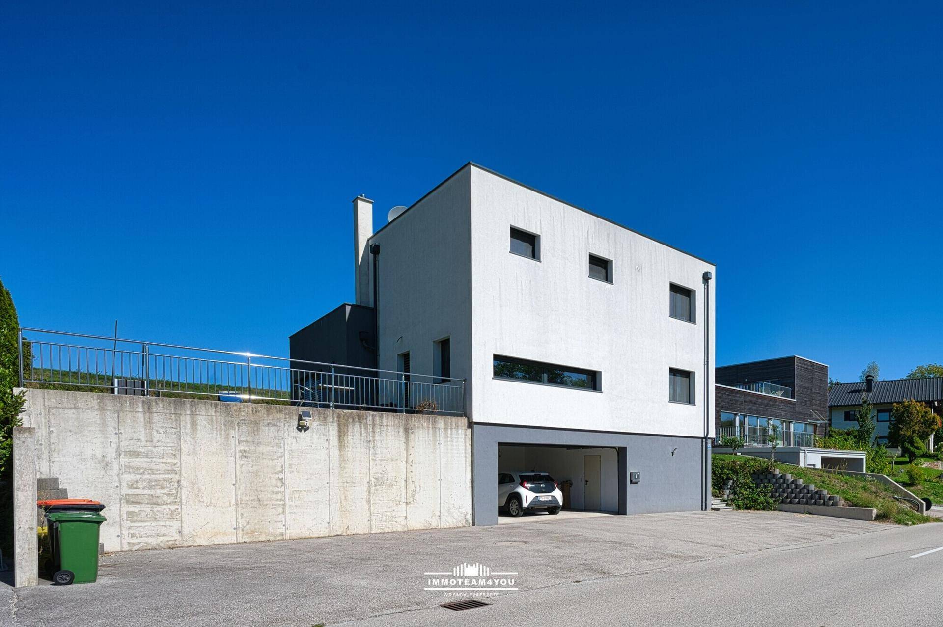 Ansicht des modernen Hauses mit integrierter Garage und Zufahrt von der Straße.