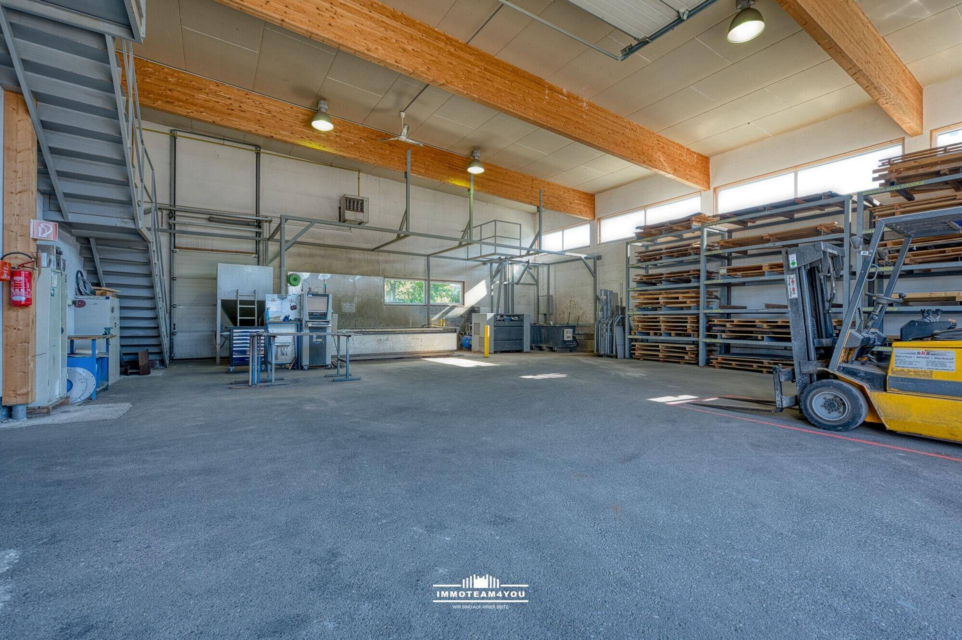 Industrielle Lagerhalle mit Holzbalken, Betonboden und Gabelstapler.