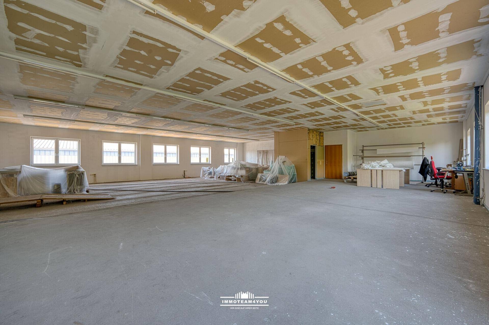 Geräumiges Büro in Renovierung mit unfertiger Decke und Blick ins Grüne.