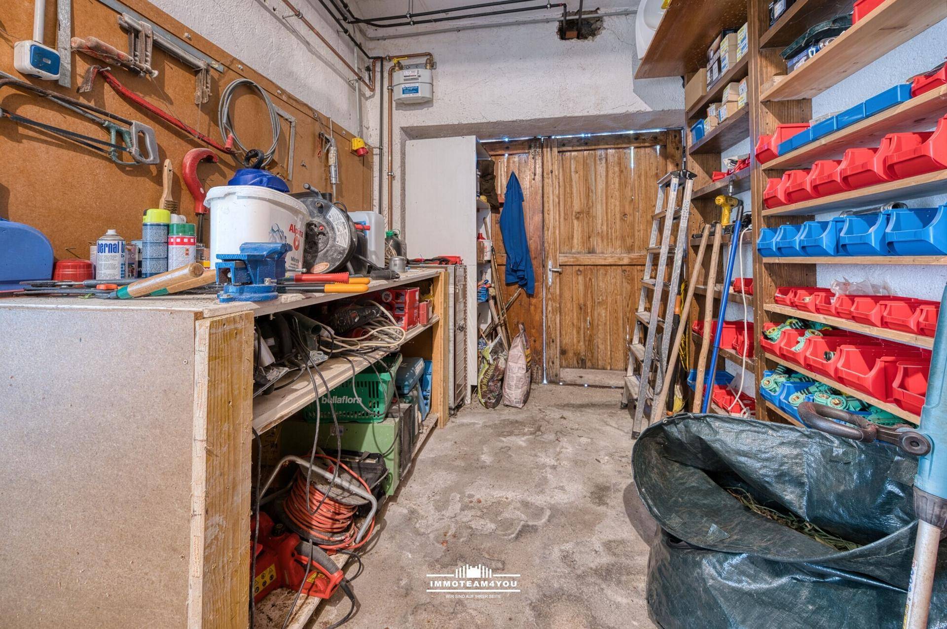 Werkstattraum mit Regalen, Werkzeugen und Holztür.