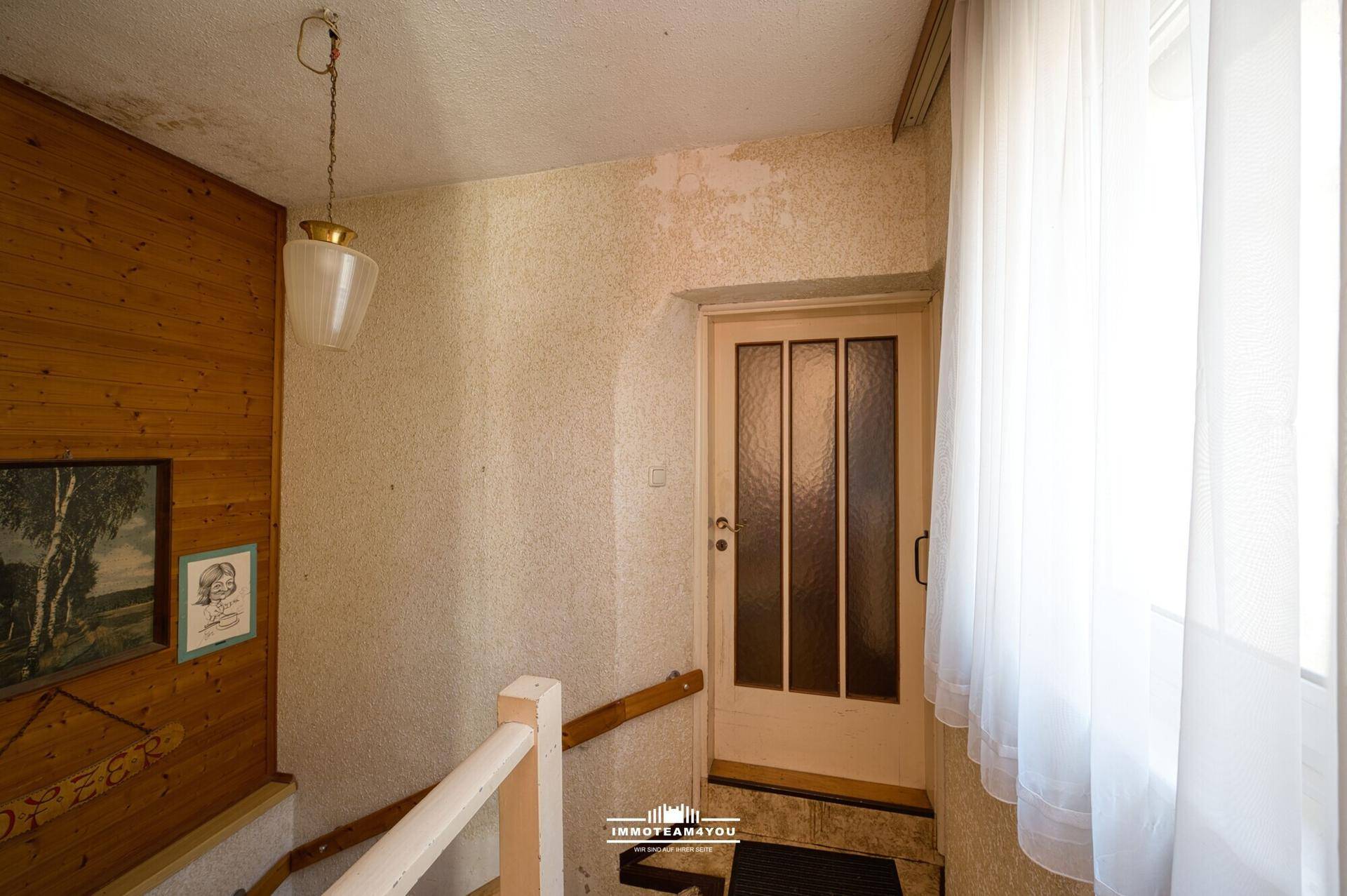 Heller Flur mit Holzvertäfelung, Treppe und Eingangstür.