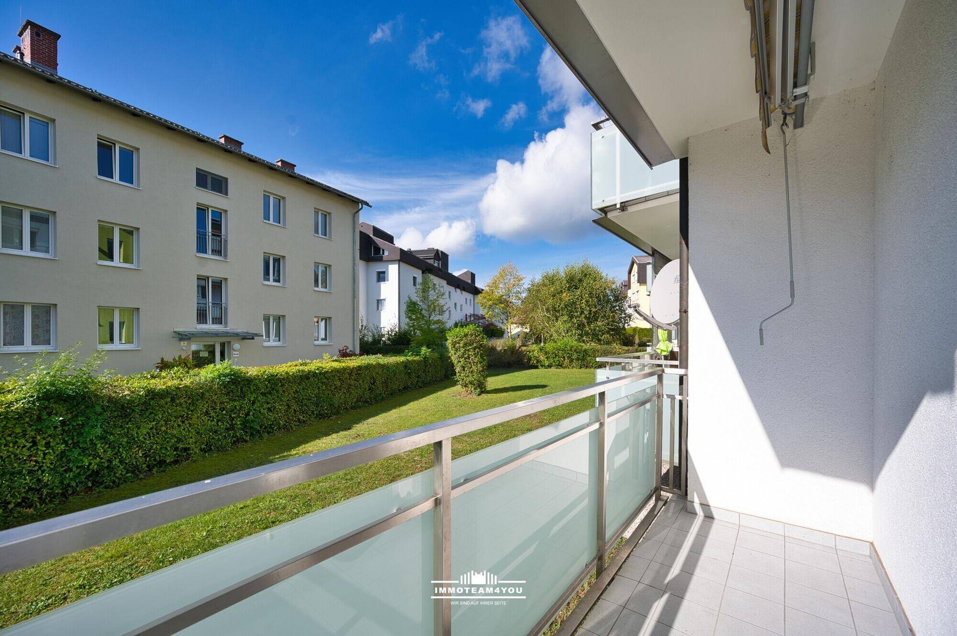Balkon mit Blick auf den grünen Innenhof und umliegende Gebäude.