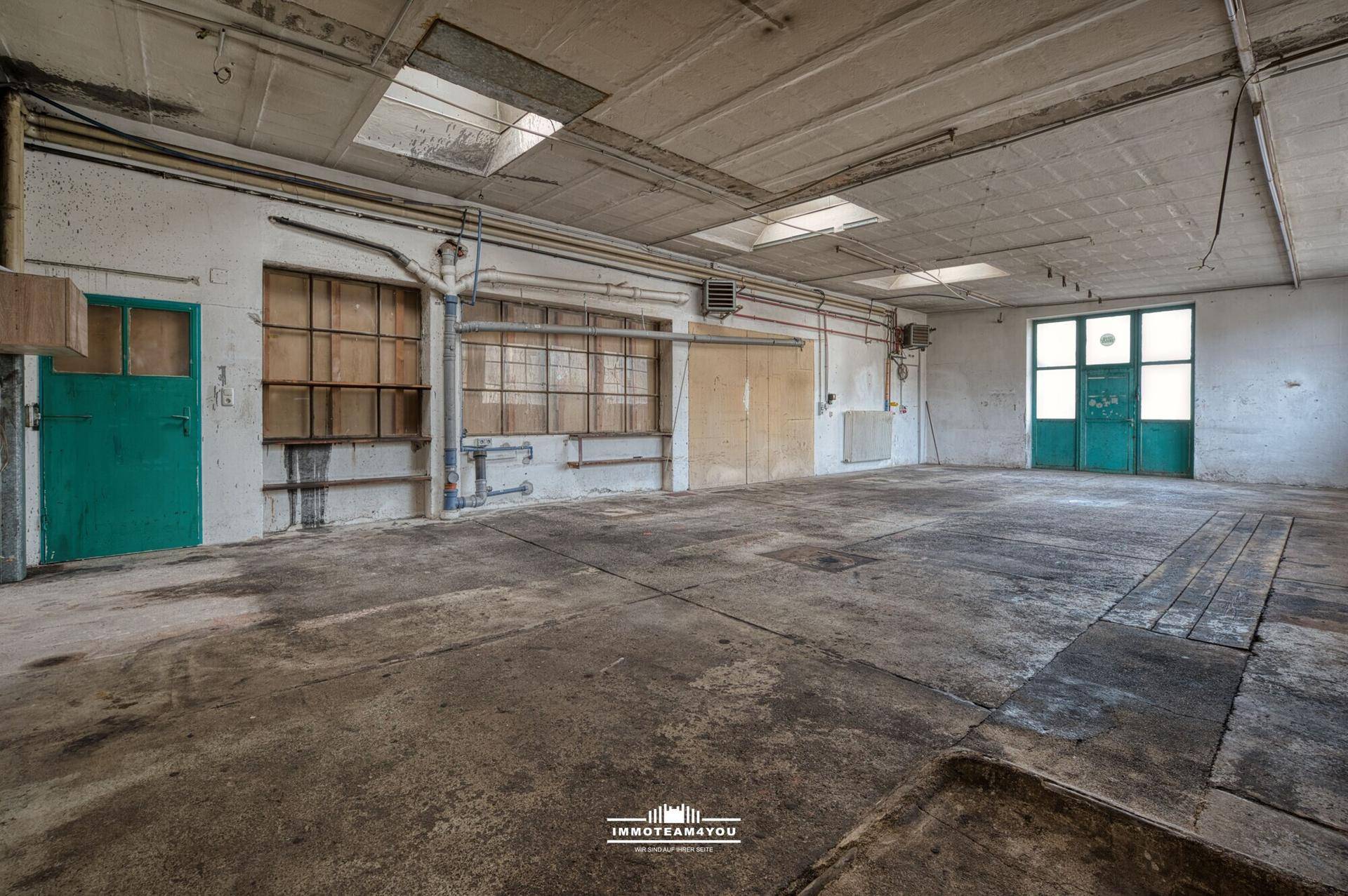 Große Werkstatt mit Betonboden, Oberlichtern und industriellem Charme, viel Platz für Projekte.