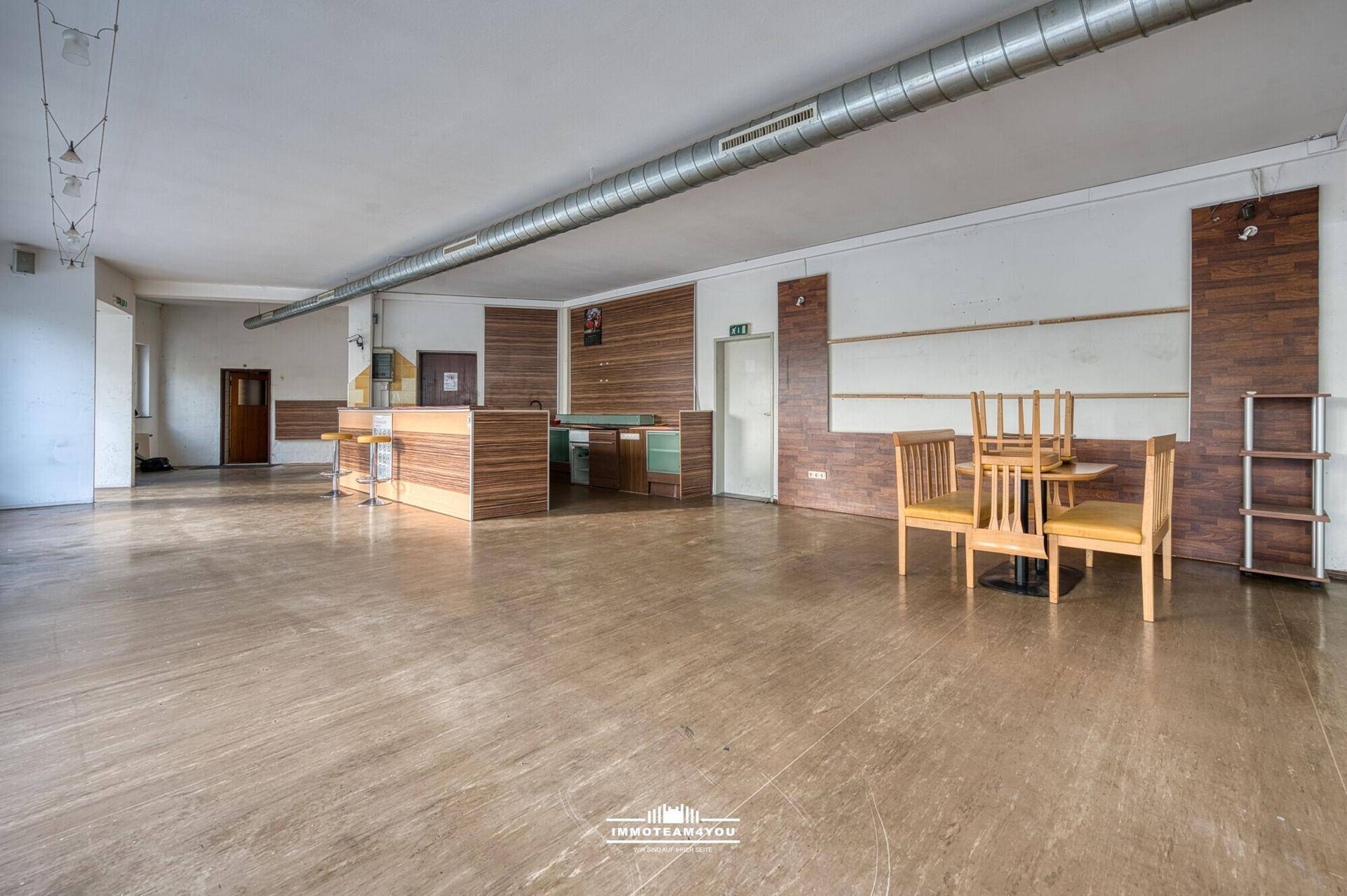 Großer, offener Raum mit Theke und Tischen, ideal für eine Neugestaltung und Modernisierung.