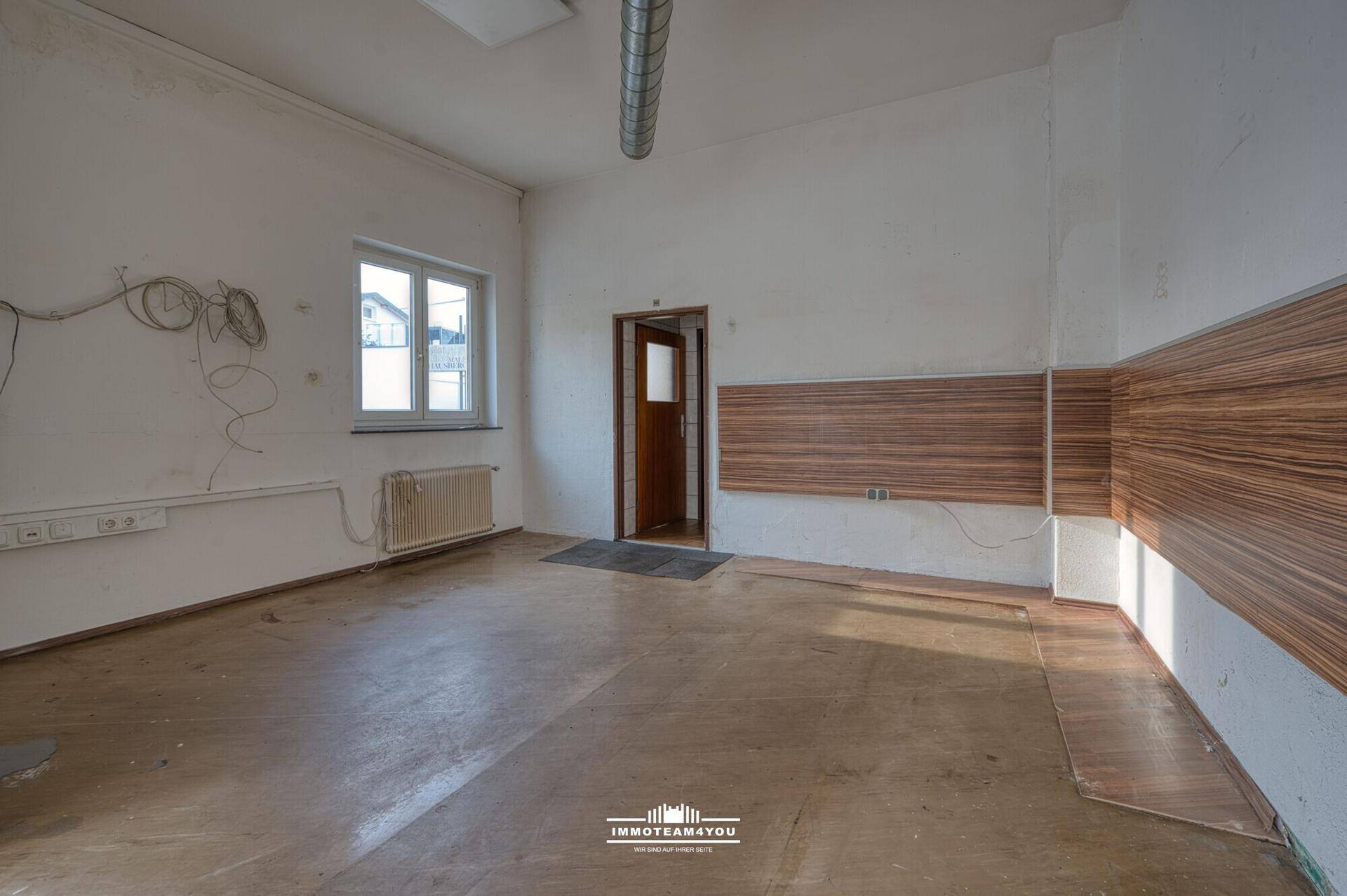 Kleiner Raum mit Fenster, Heizkörper und Holzakzenten, ideal als Büro oder Abstellraum.