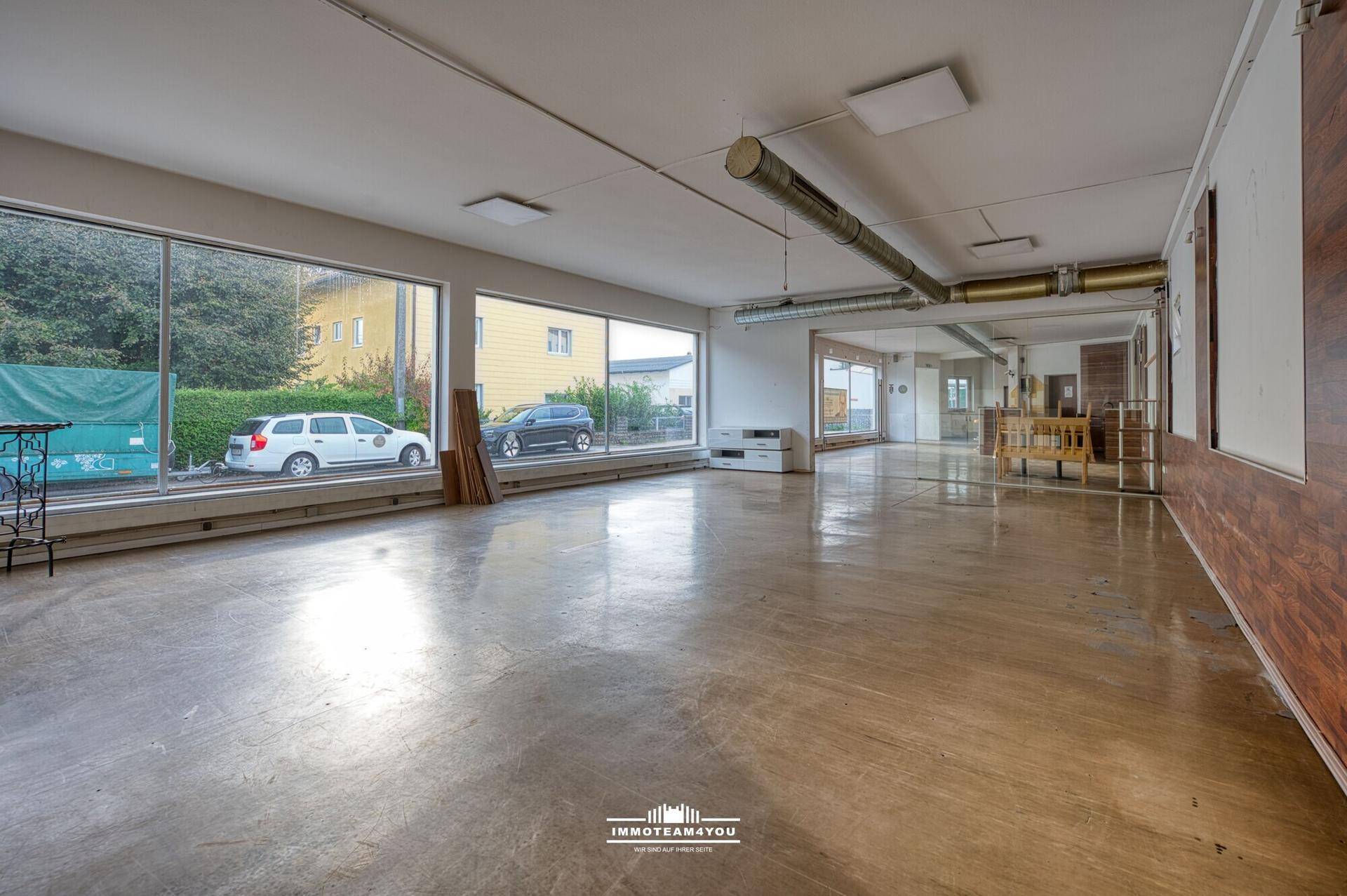 Geräumiger, leerer Raum mit großen Fenstern und Blick auf die Straße, ideal für Umbauprojekte.