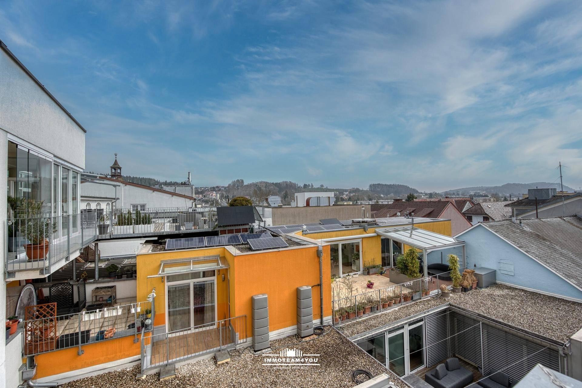 Weitläufige Dachlandschaft mit verschiedenen Gebäuden, Dachterrassen und Solaranlagen.