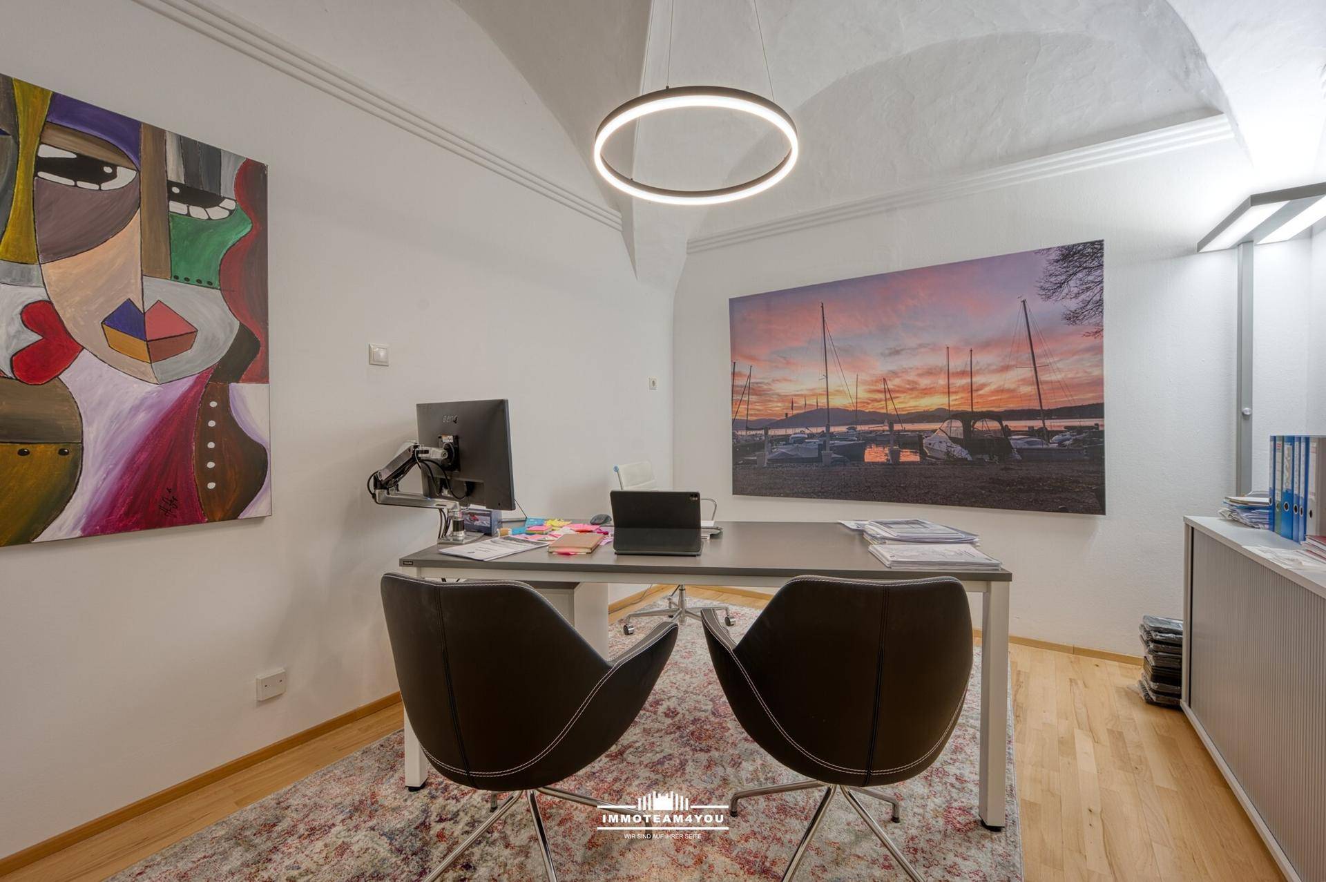 Elegantes Büro mit gewölbter Decke, modernem Schreibtisch und Kunstwerken an den Wänden.