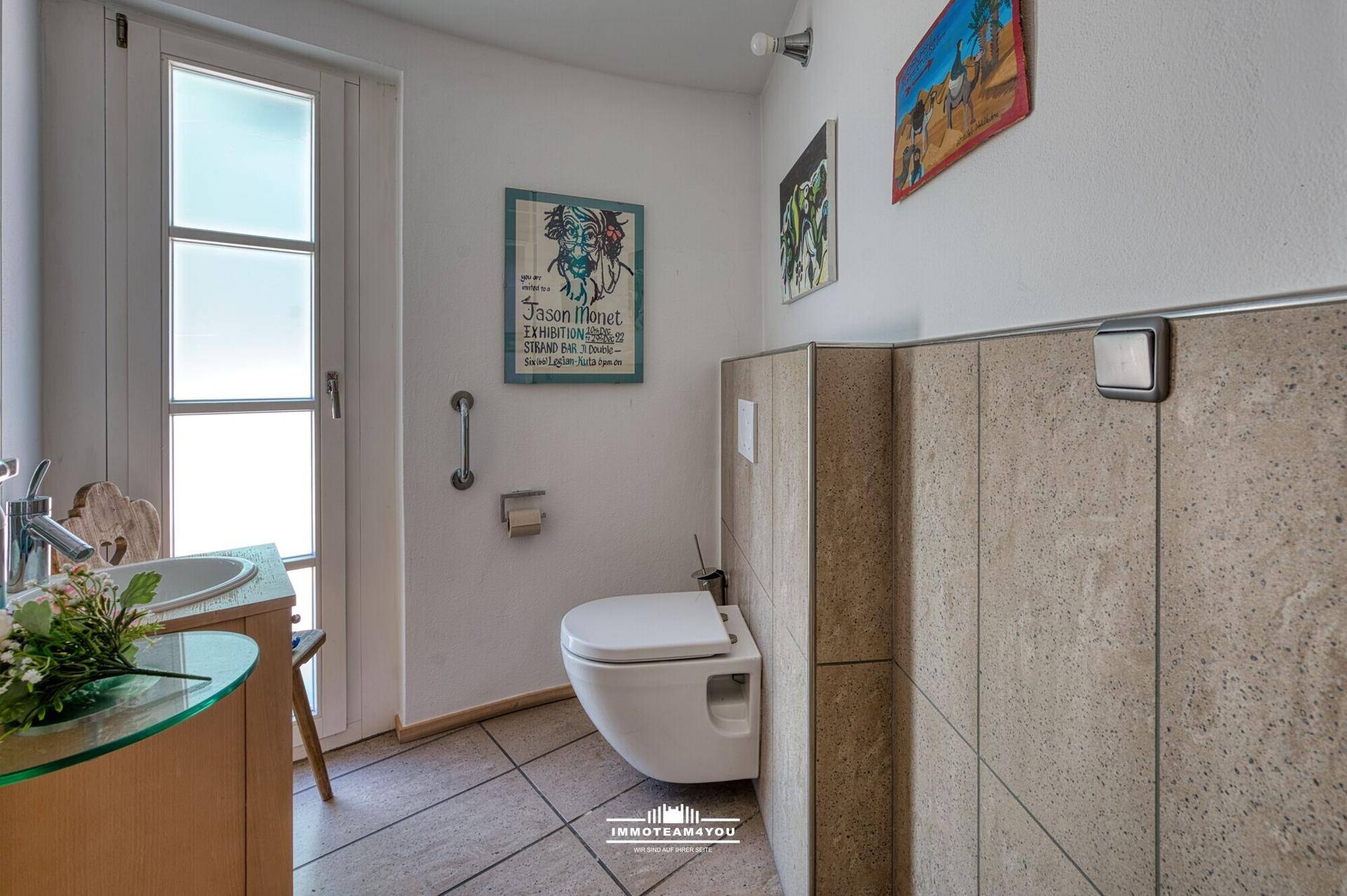 Modernes Gäste-WC mit wandhängendem WC, Waschbecken und teilweise gefliesten Wänden.