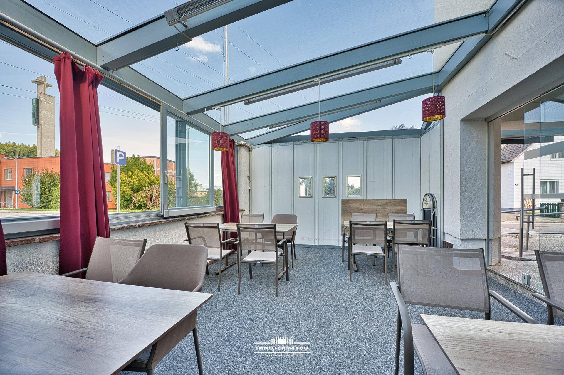 Heller Wintergarten mit Glasdach, Tischen und Stühlen, ideal für entspannte Stunden.