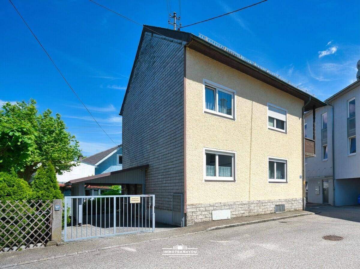 Seitenansicht des Hauses mit Schieferverkleidung, Fenstern und angrenzendem Carport.