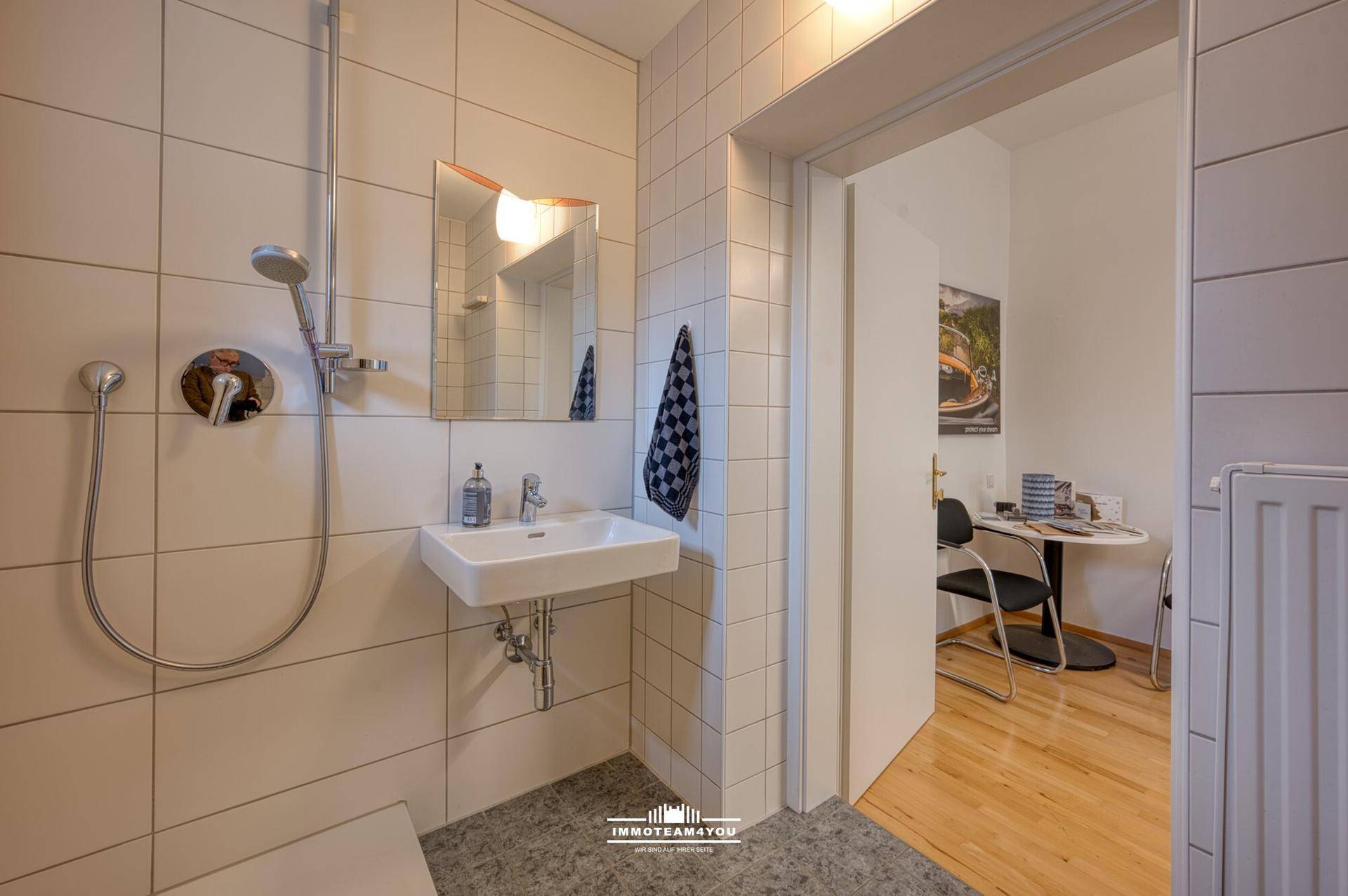 Modernes Badezimmer mit Duschbereich, Waschbecken und weißen Wandfliesen.