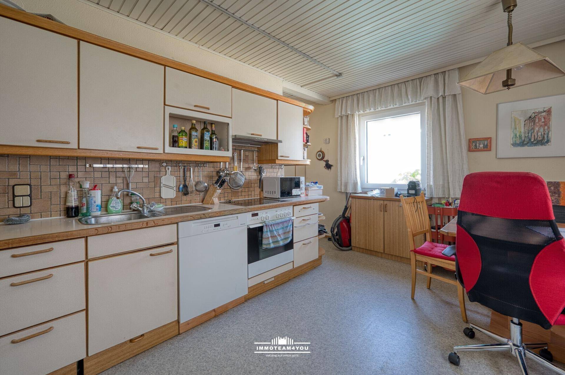 Funktionale Küche mit weißen Schränken, integrierten Geräten und einem Fenster.