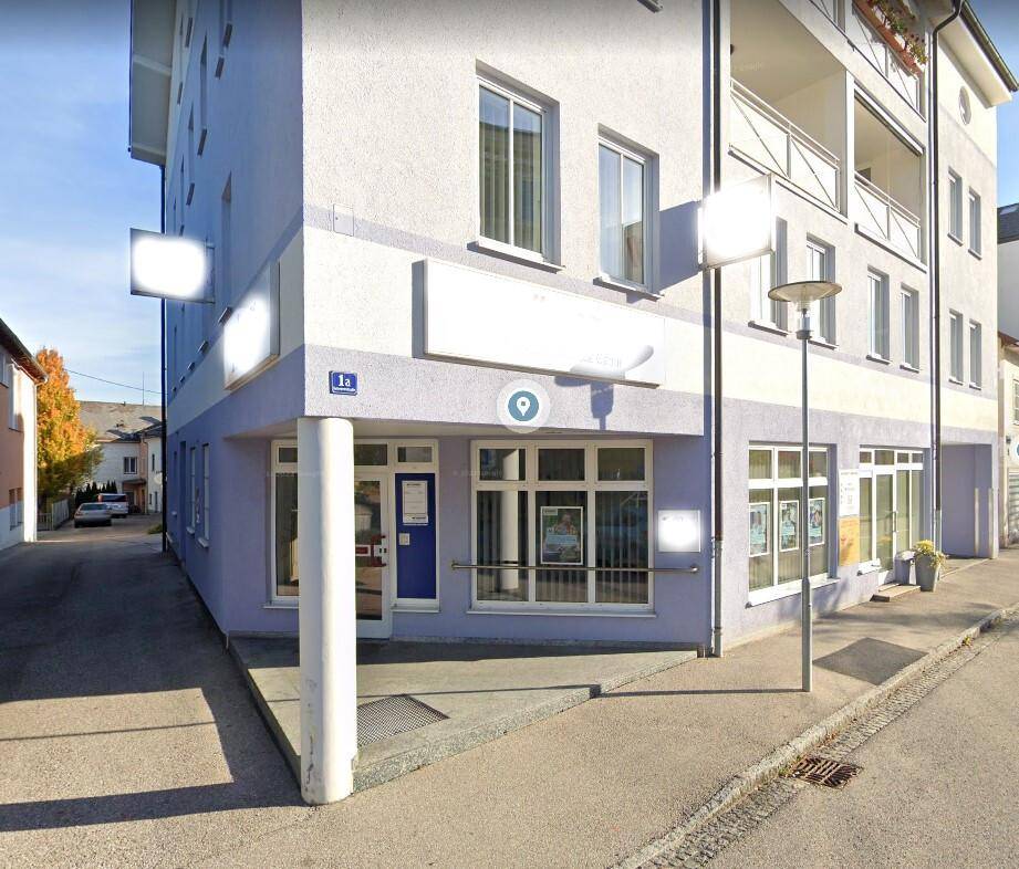 Modernes Geschäftsgebäude mit hellvioletter Fassade und großen Fenstern an einer Straßenecke.